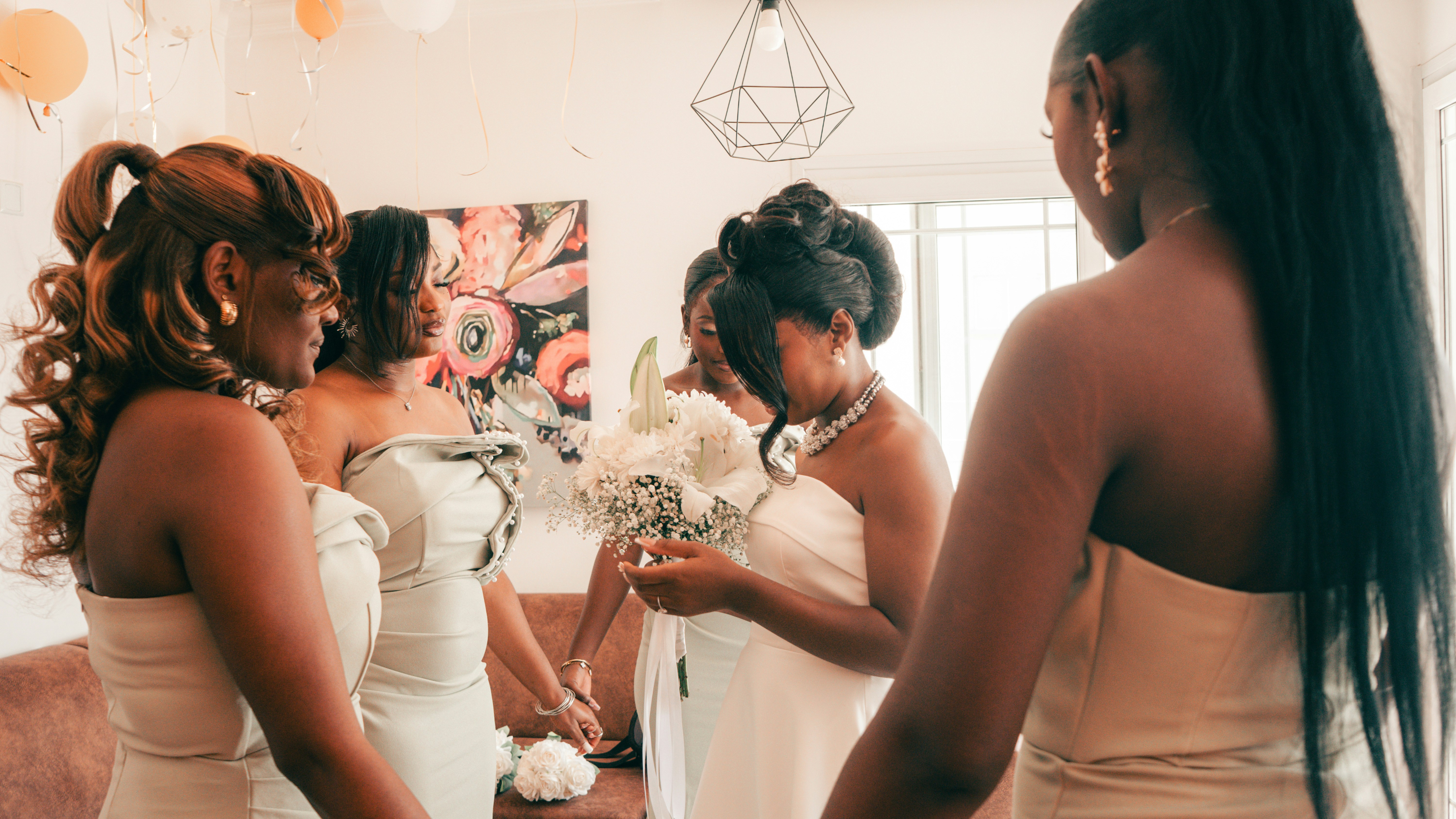 Bridesmaids in light dresses holding a white floral bouquet.