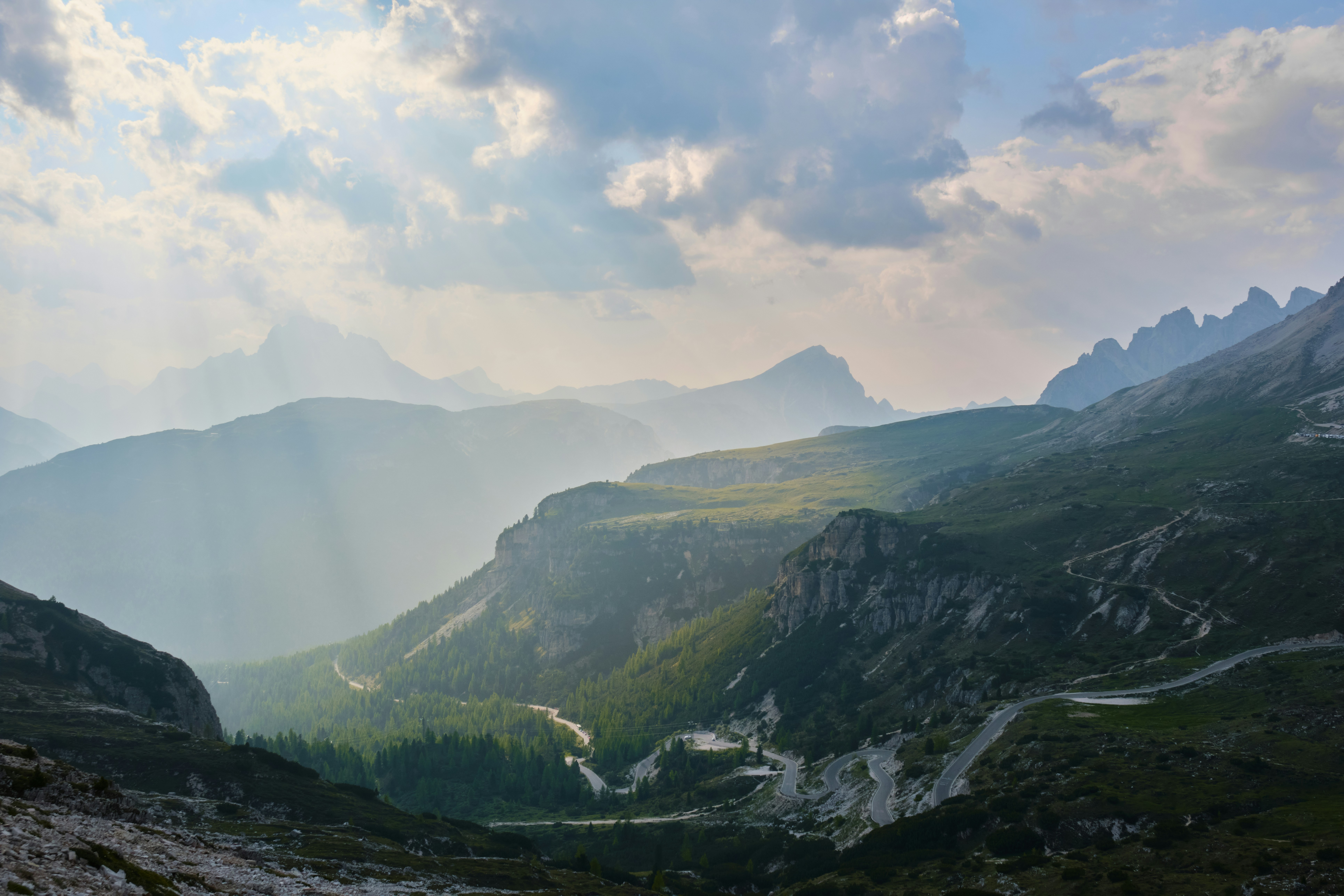 Dramatic mountain valley illuminated by sun rays through cloudy sky.