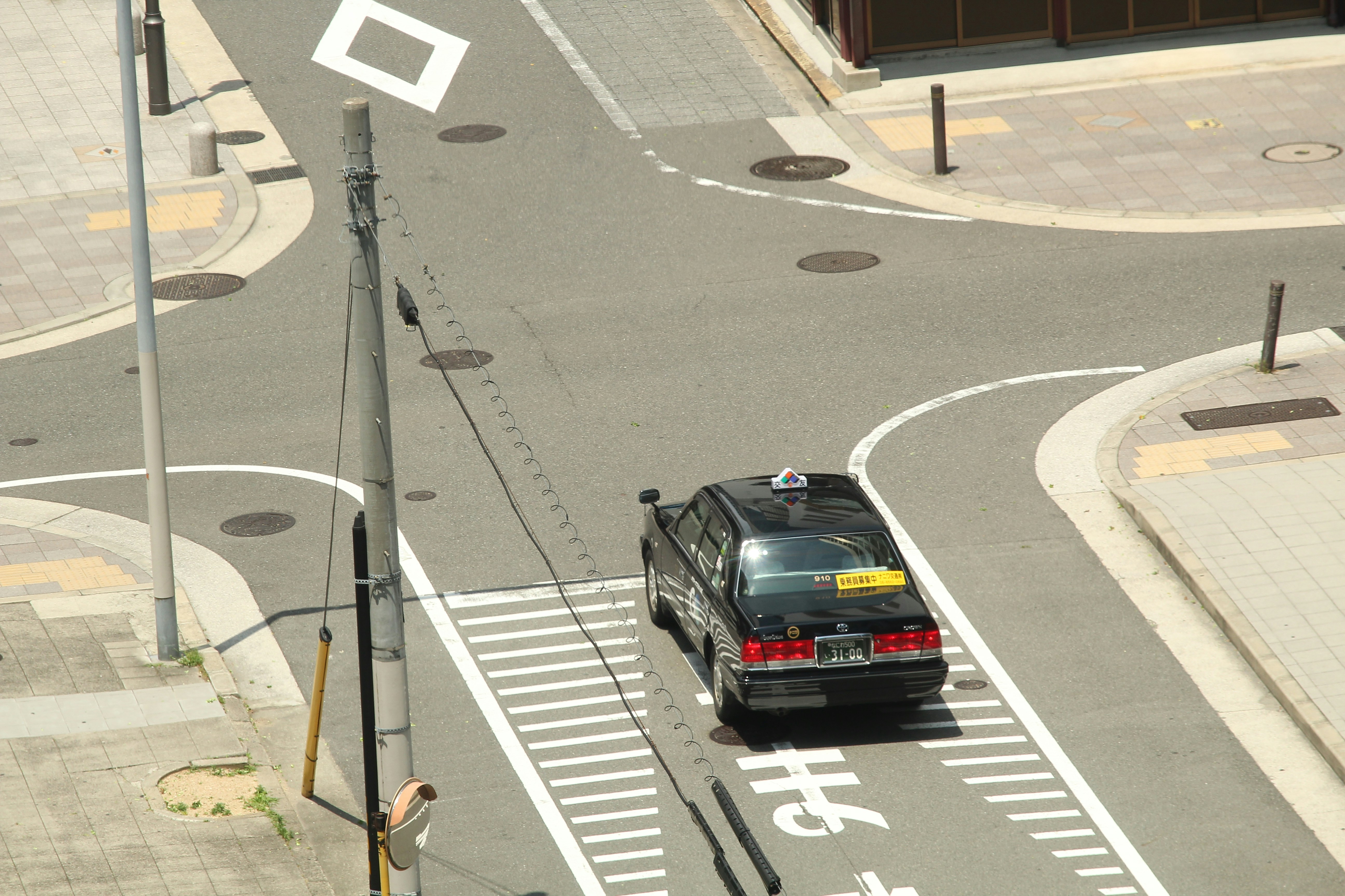 A black taxi cab drives through a city intersection