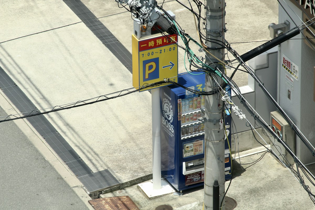 日本街角的停車場招牌，寫著營業時間 7:00 到 21:00 與往右的 P 標誌