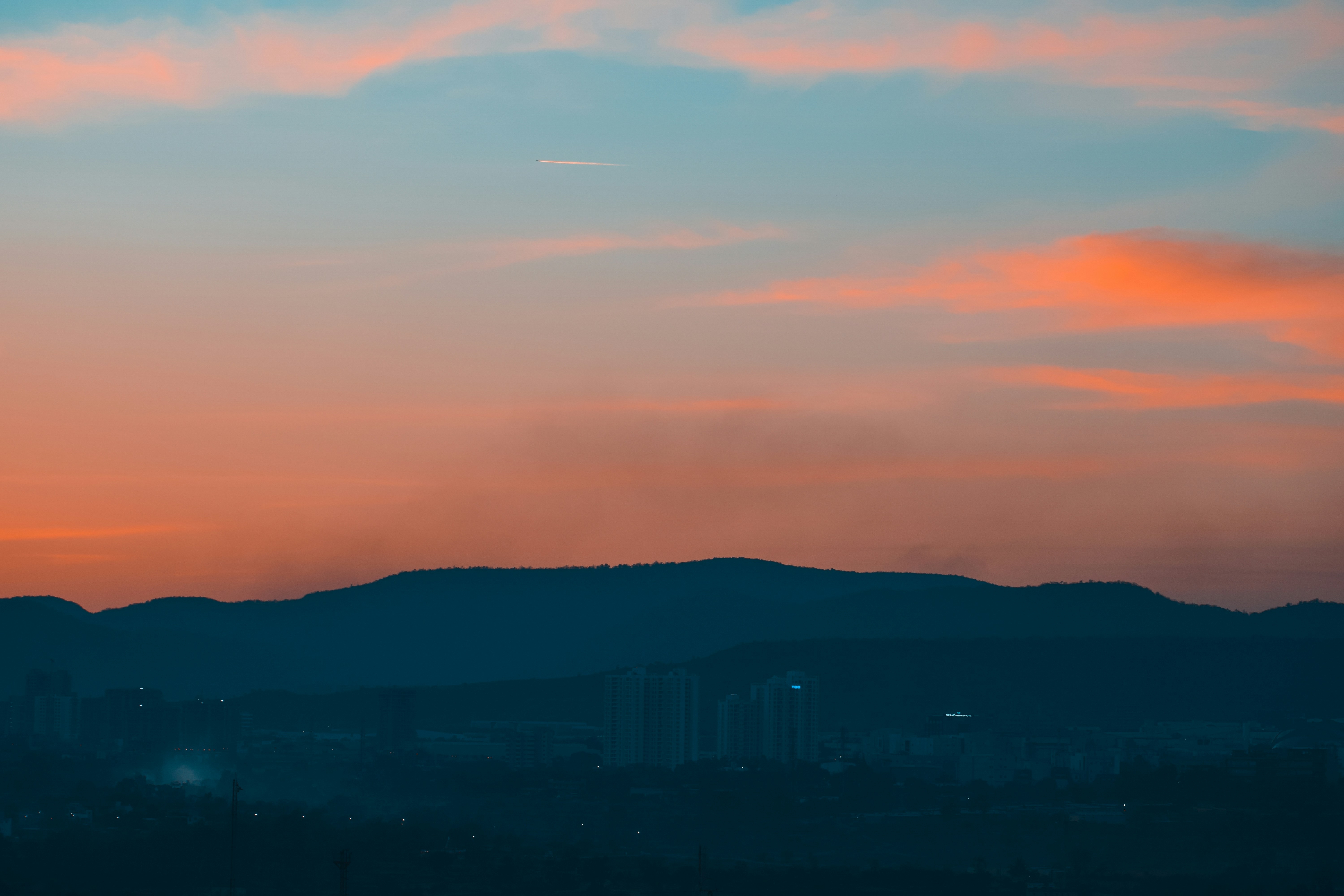 Orange and blue sunset sky over dark mountain silhouettes.