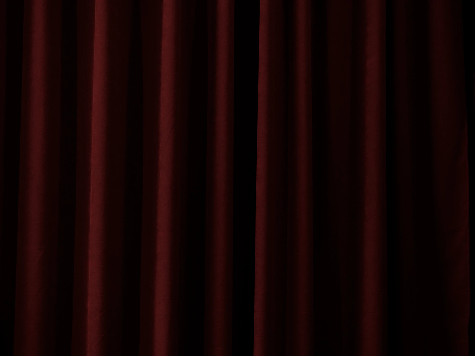 Dark red velvet curtains with vertical folds and shadows