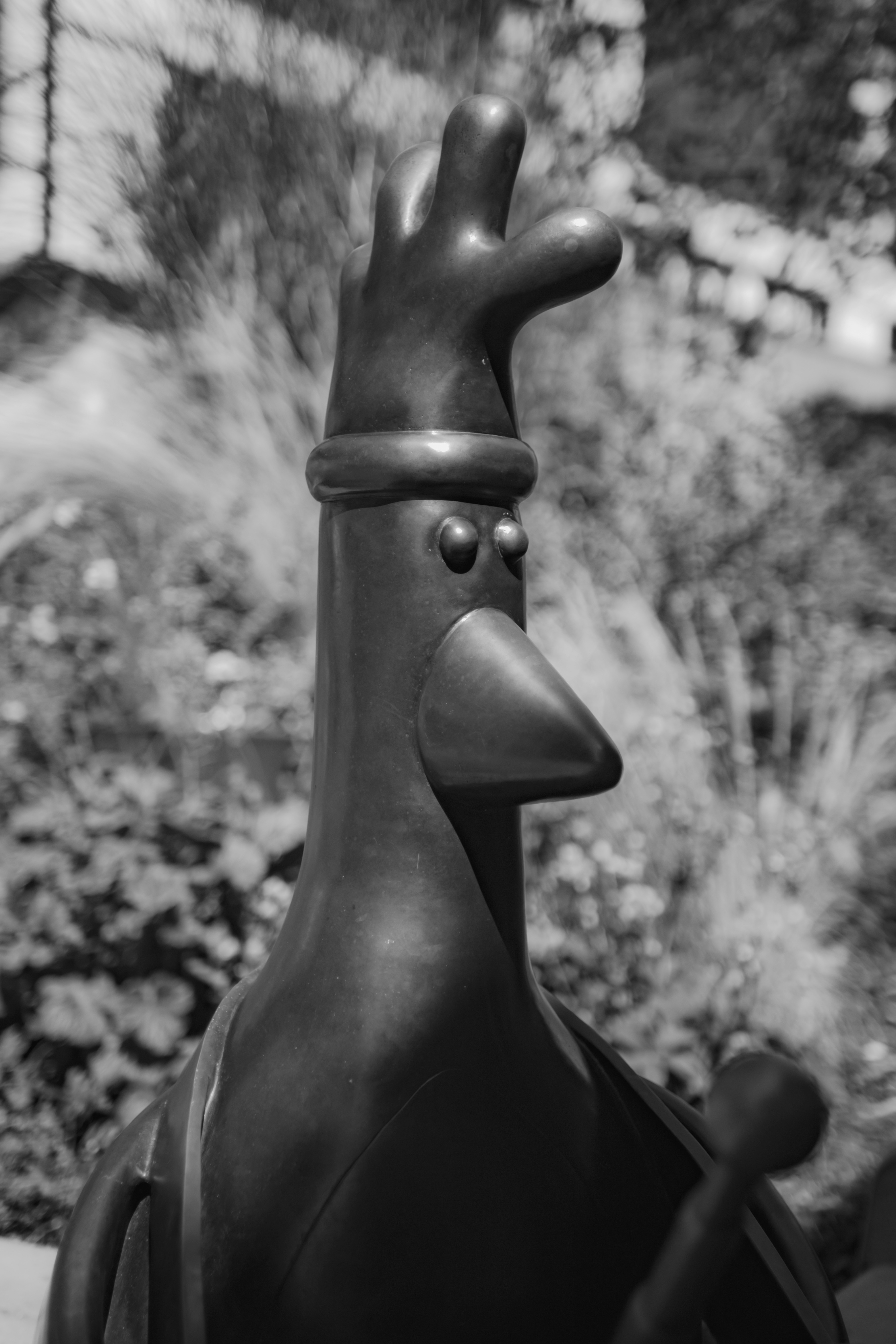 Monochrome statue of a bird wearing a hat outdoors.