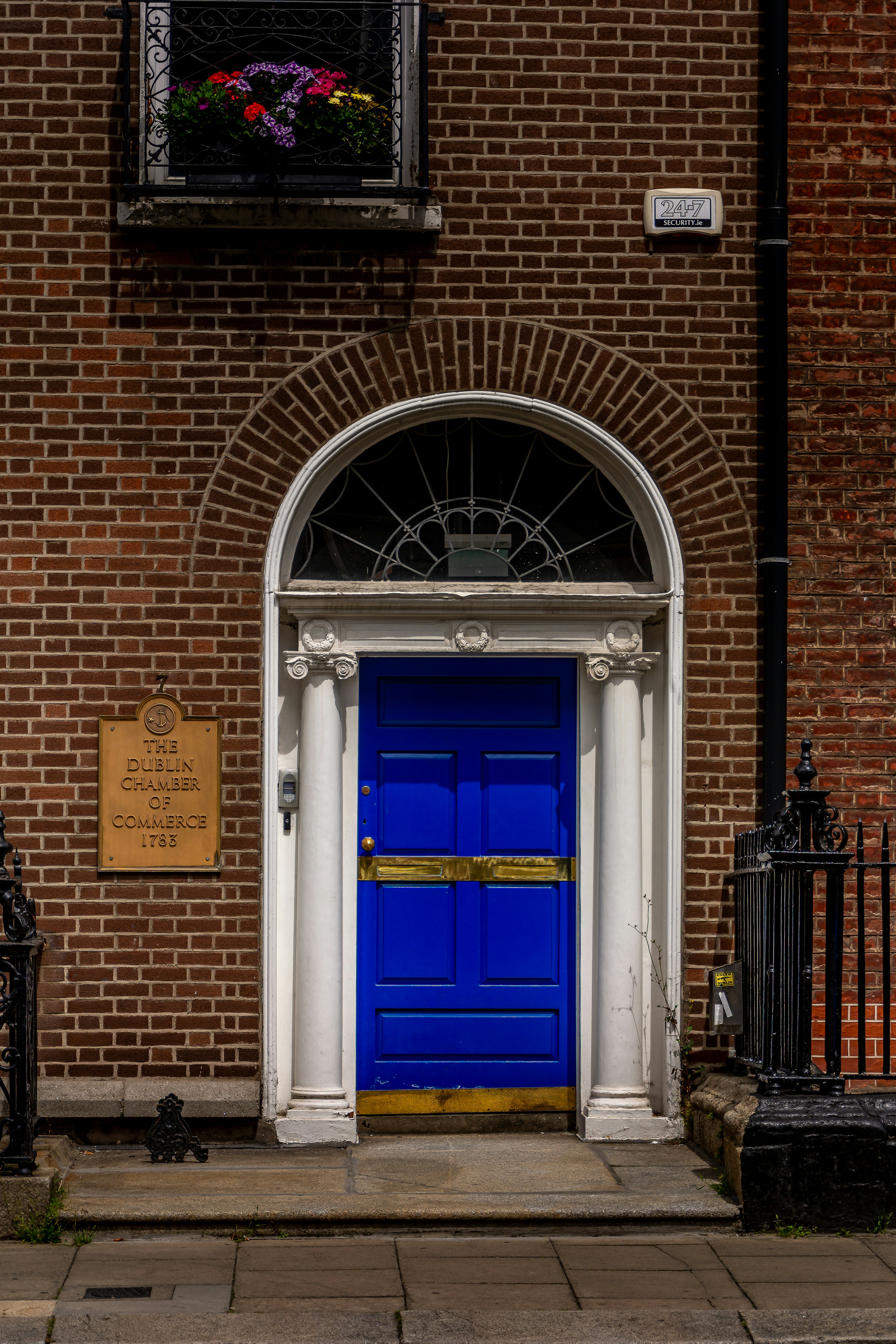 Vibrant blue door with white columns in a brick building.