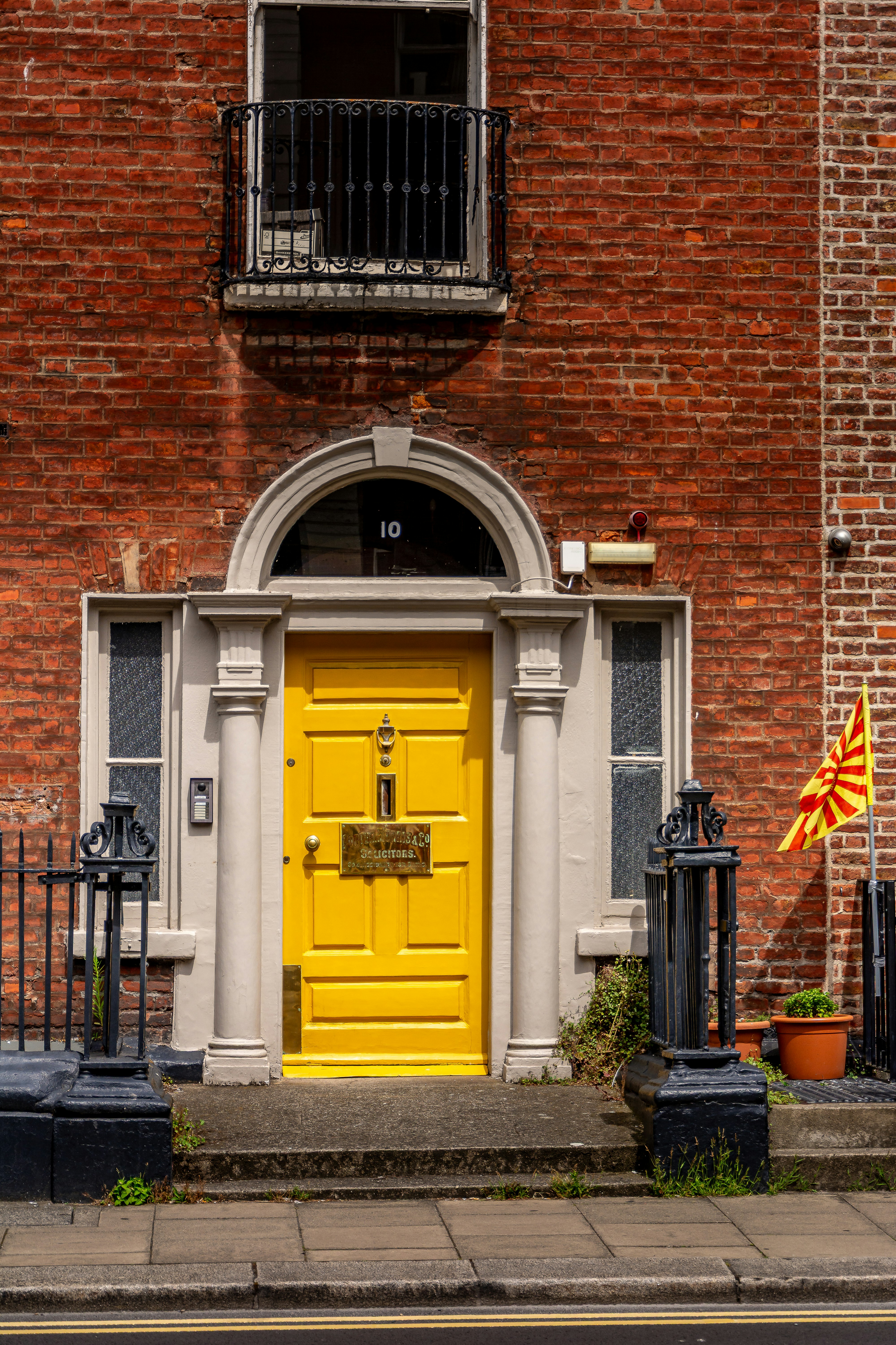 Vibrant yellow door on a classic brick building.