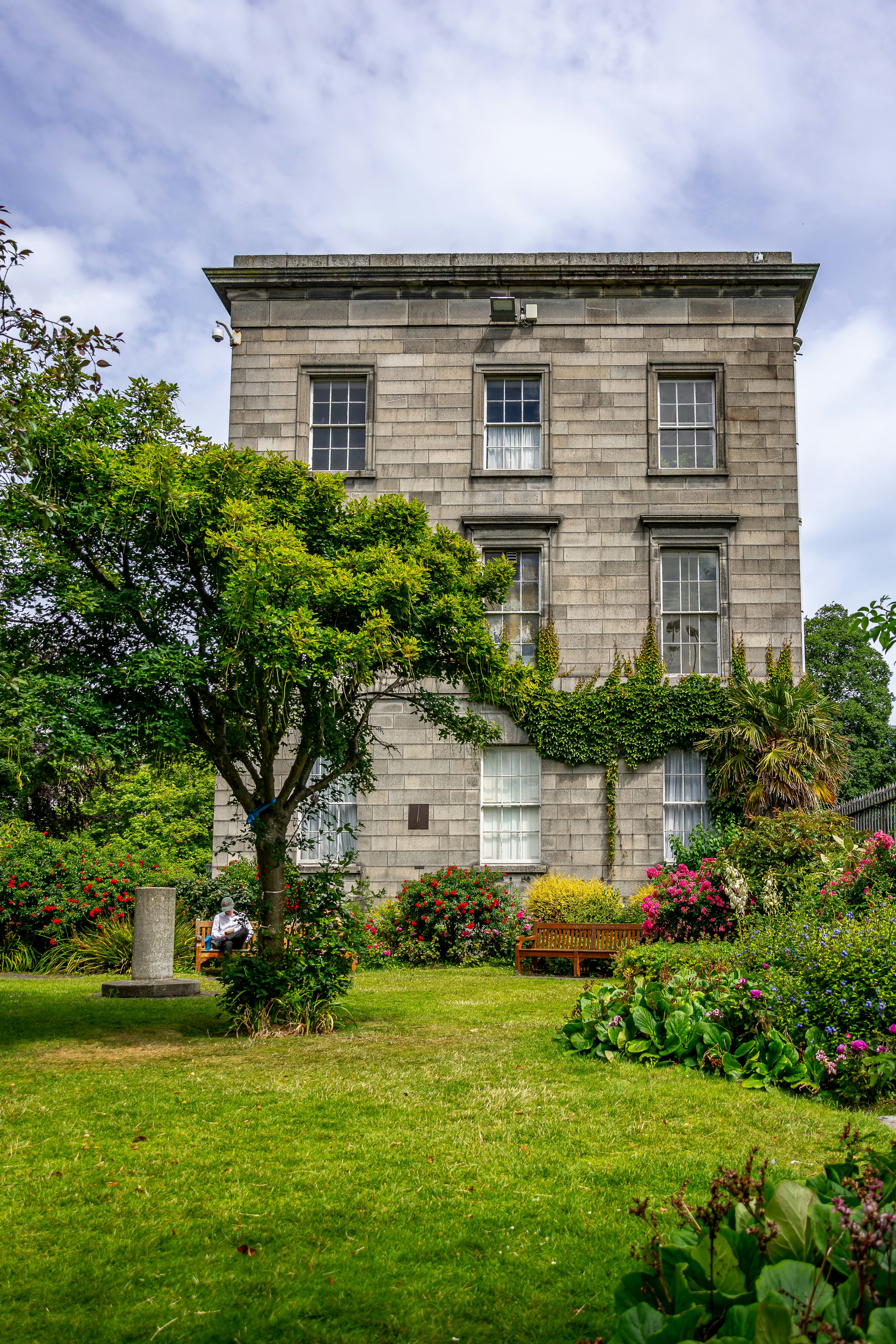 Elegant stone building with a vibrant garden and green lawn.