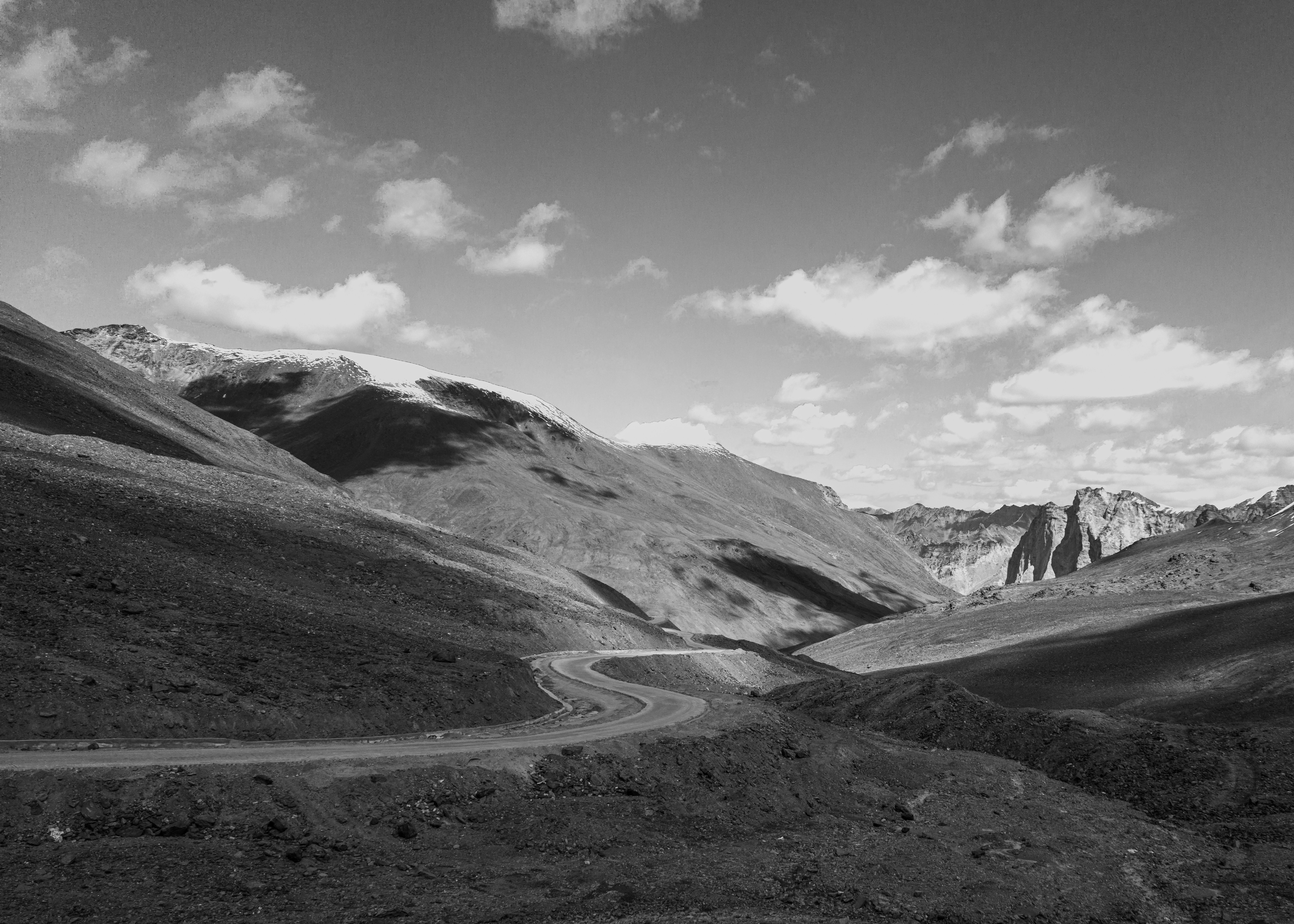Monochrome winding road through vast, rugged mountain terrain.