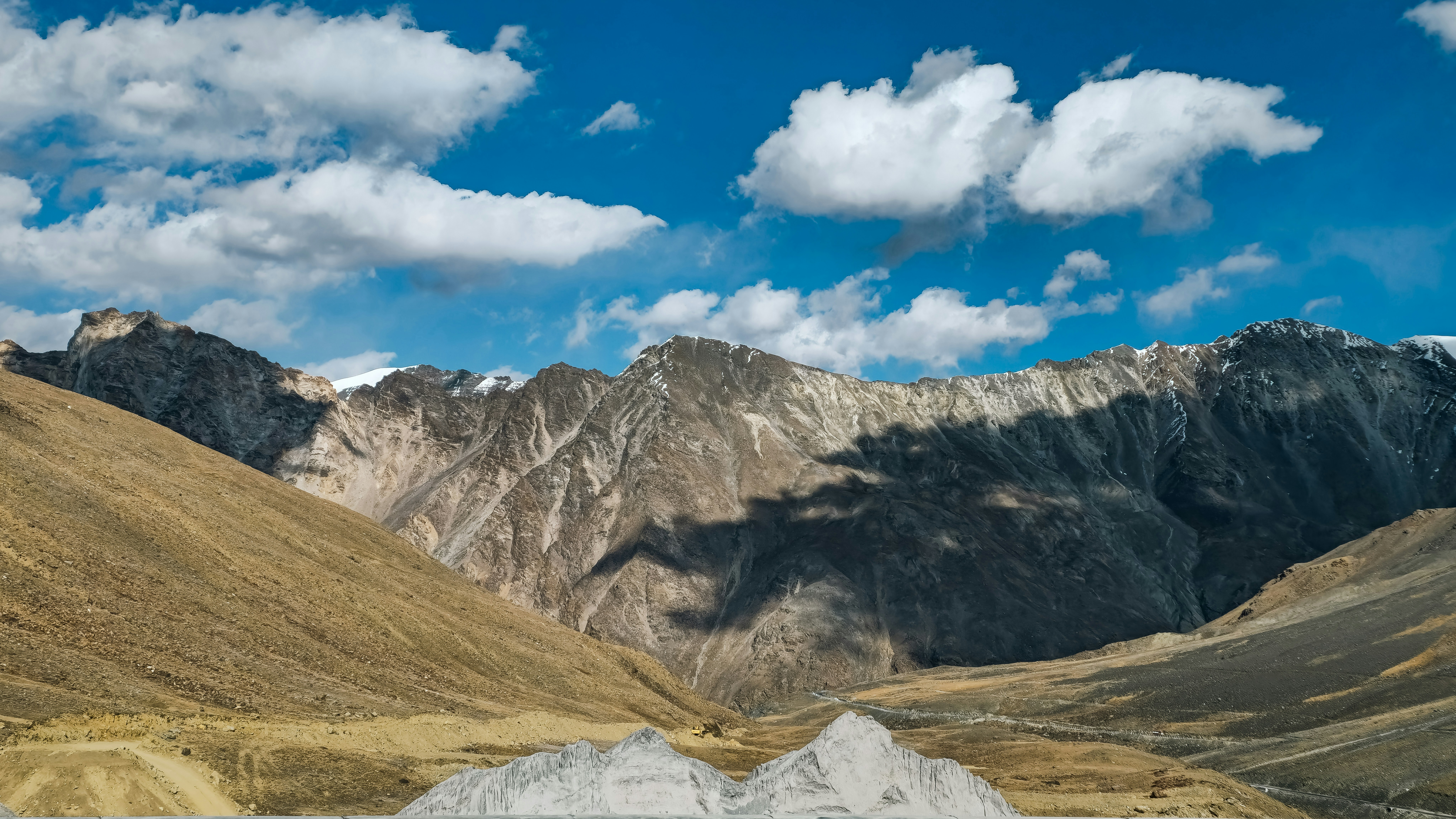 Rugged mountains under a blue sky with white clouds.