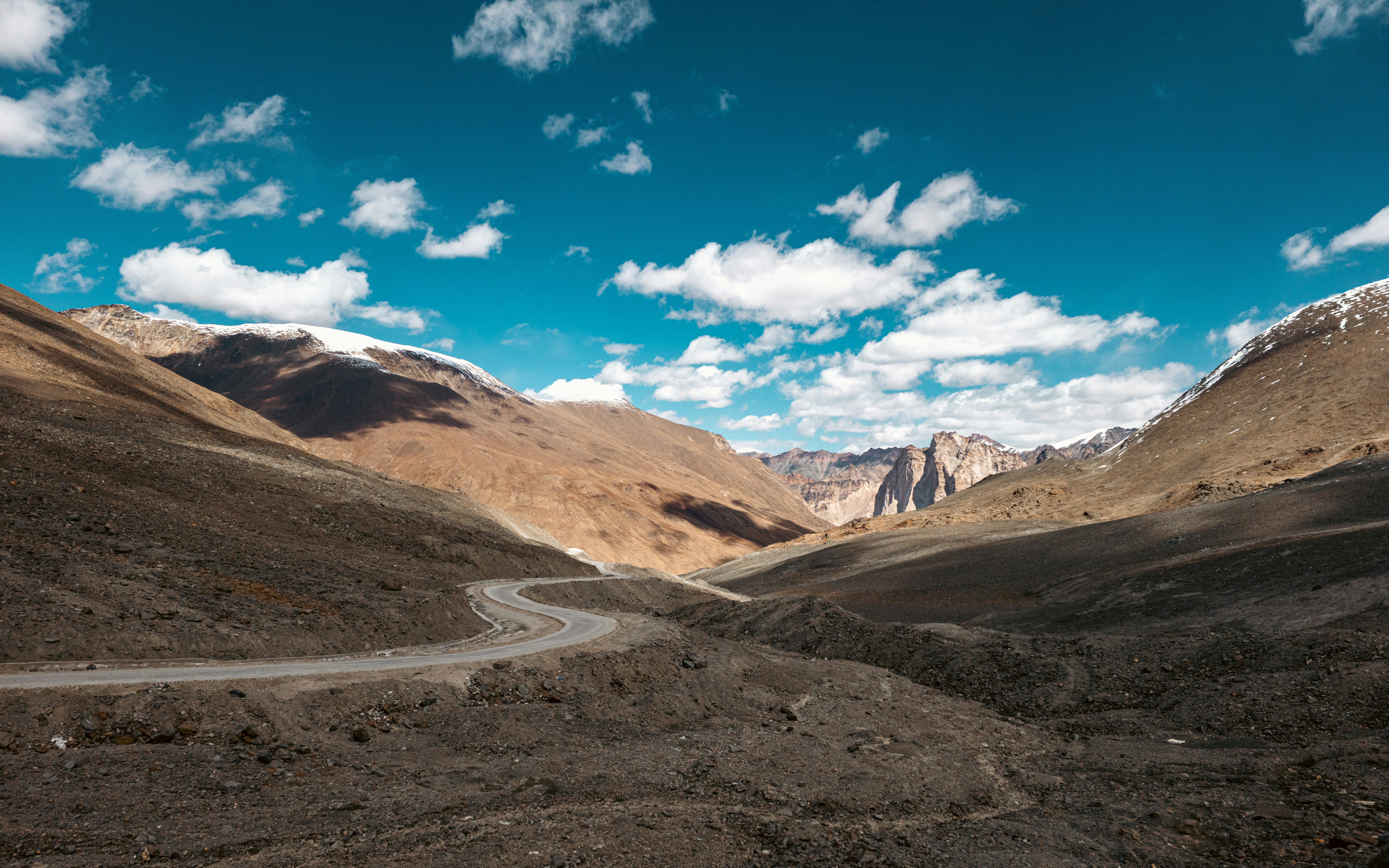 Winding road through an arid mountain valley under blue sky.