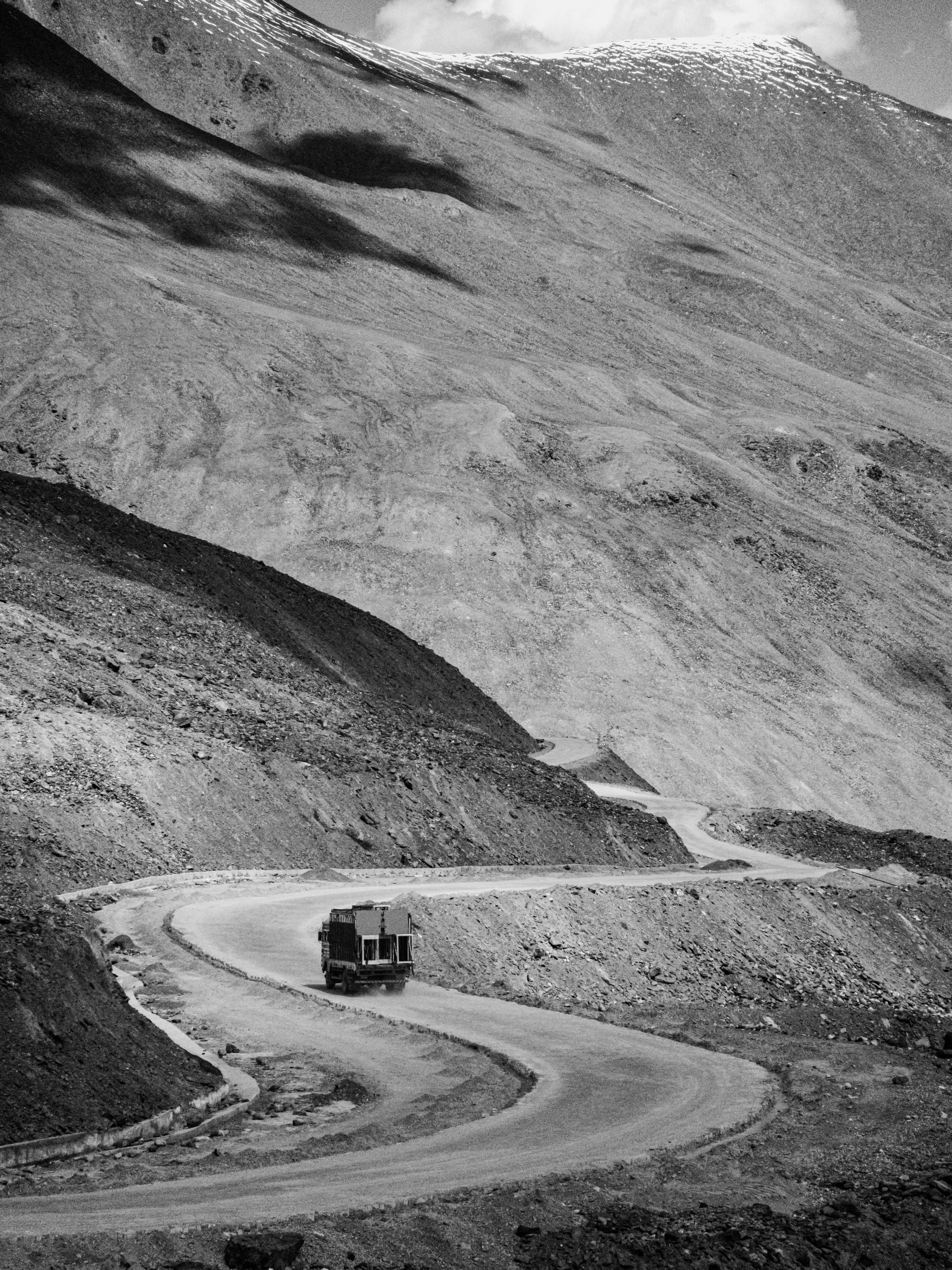 Truck on a winding mountain road, black and white.