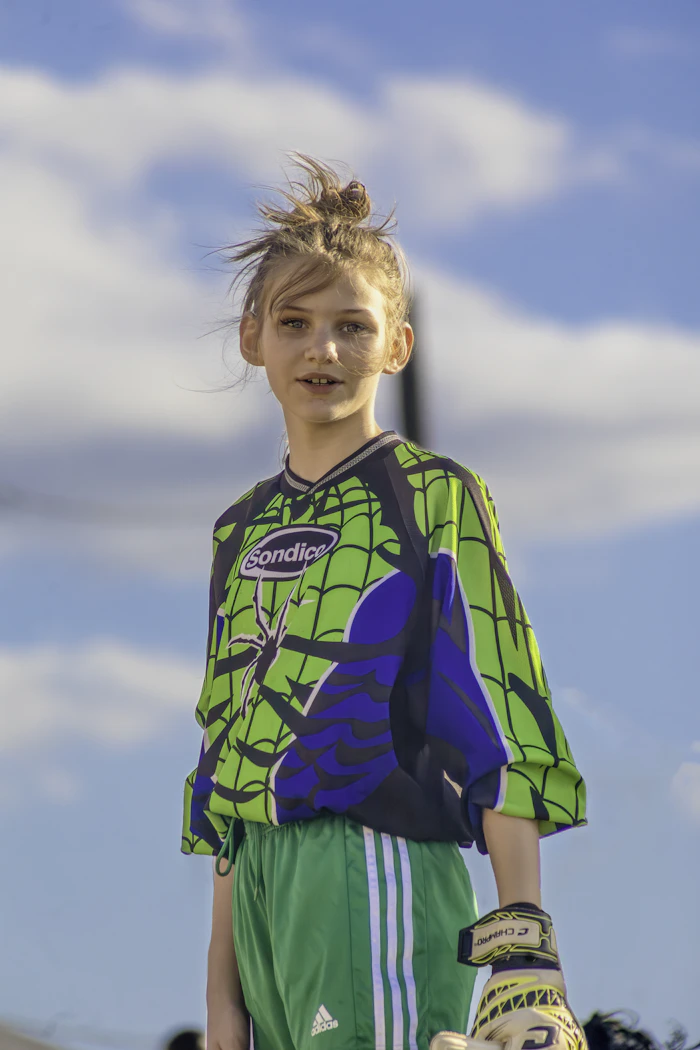 Meisje in groen keepersshirt met een keepershandschoen