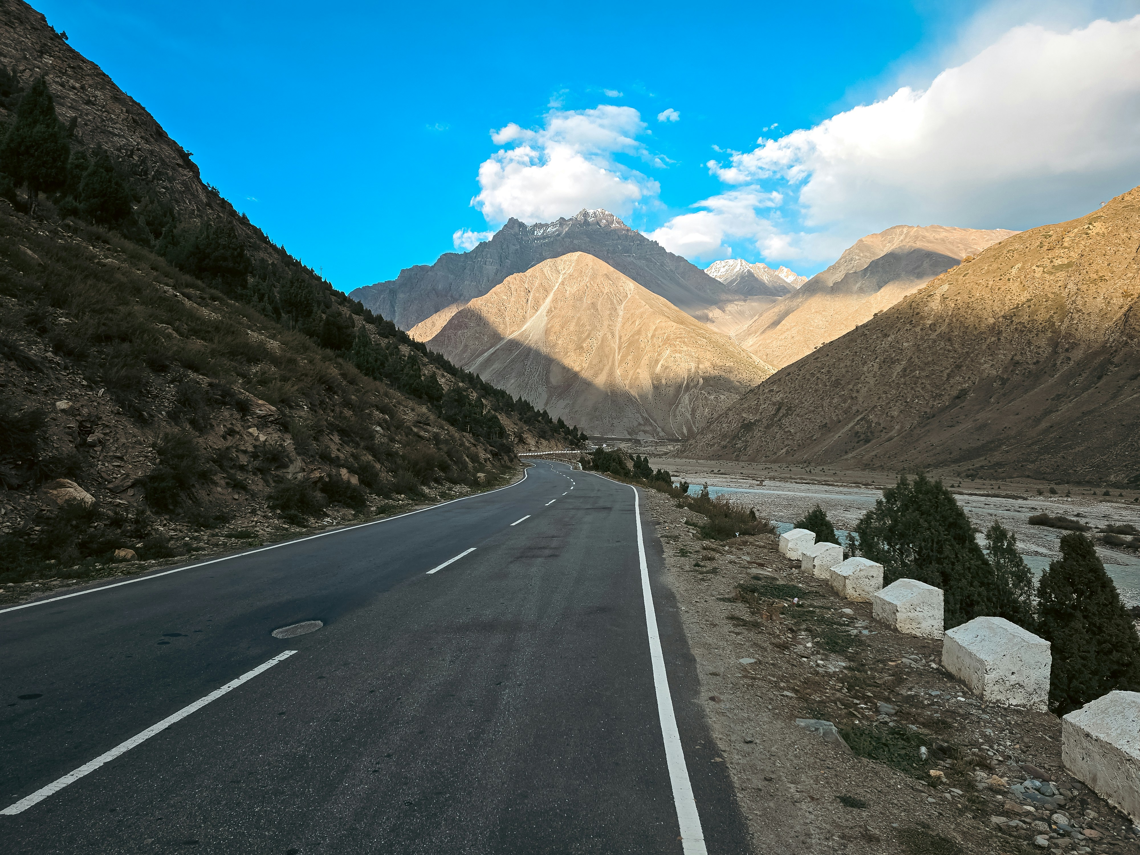 Empty road winding through a vast mountain landscape.