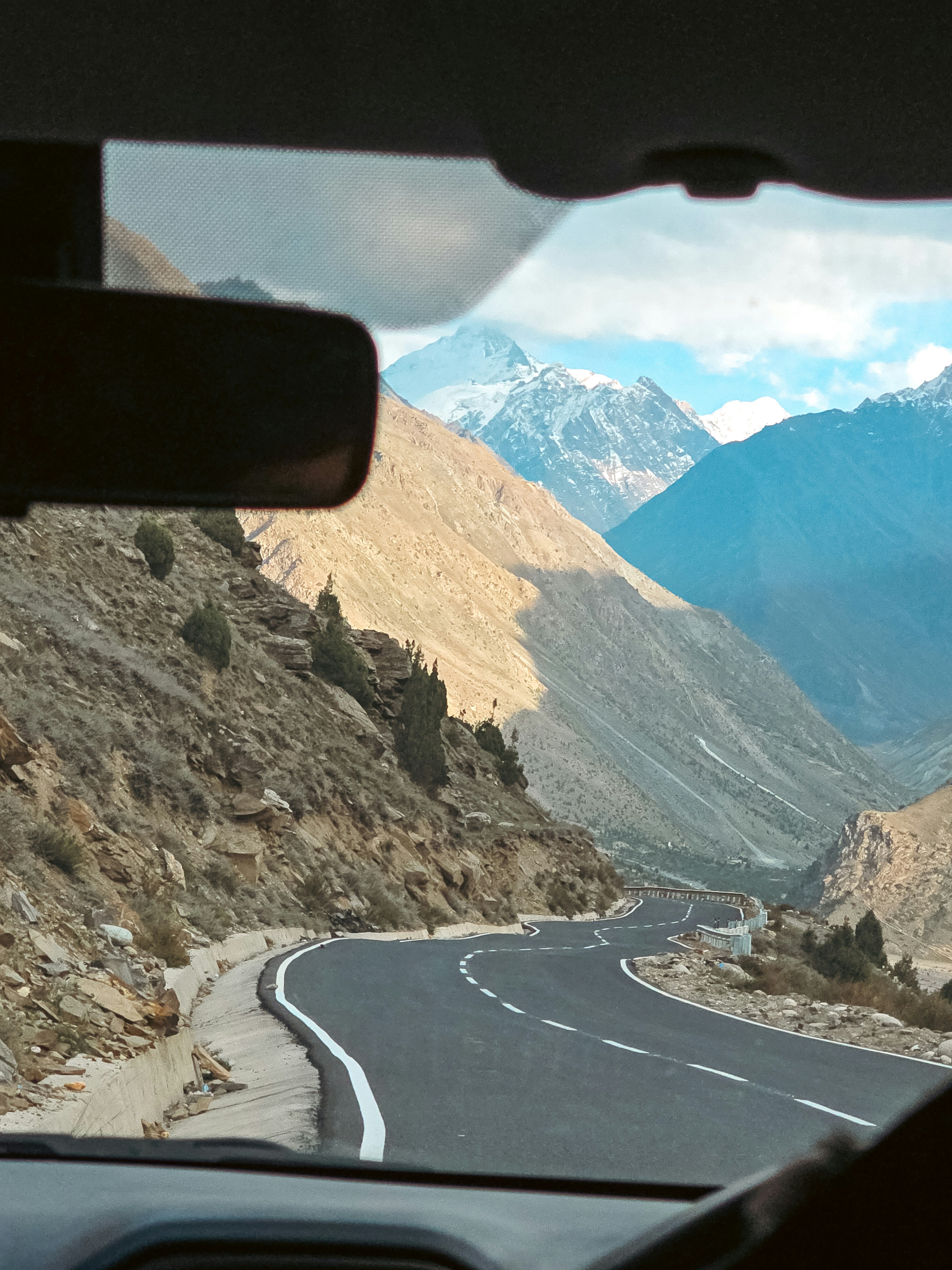 Driving through a winding mountain pass with snowy peaks.