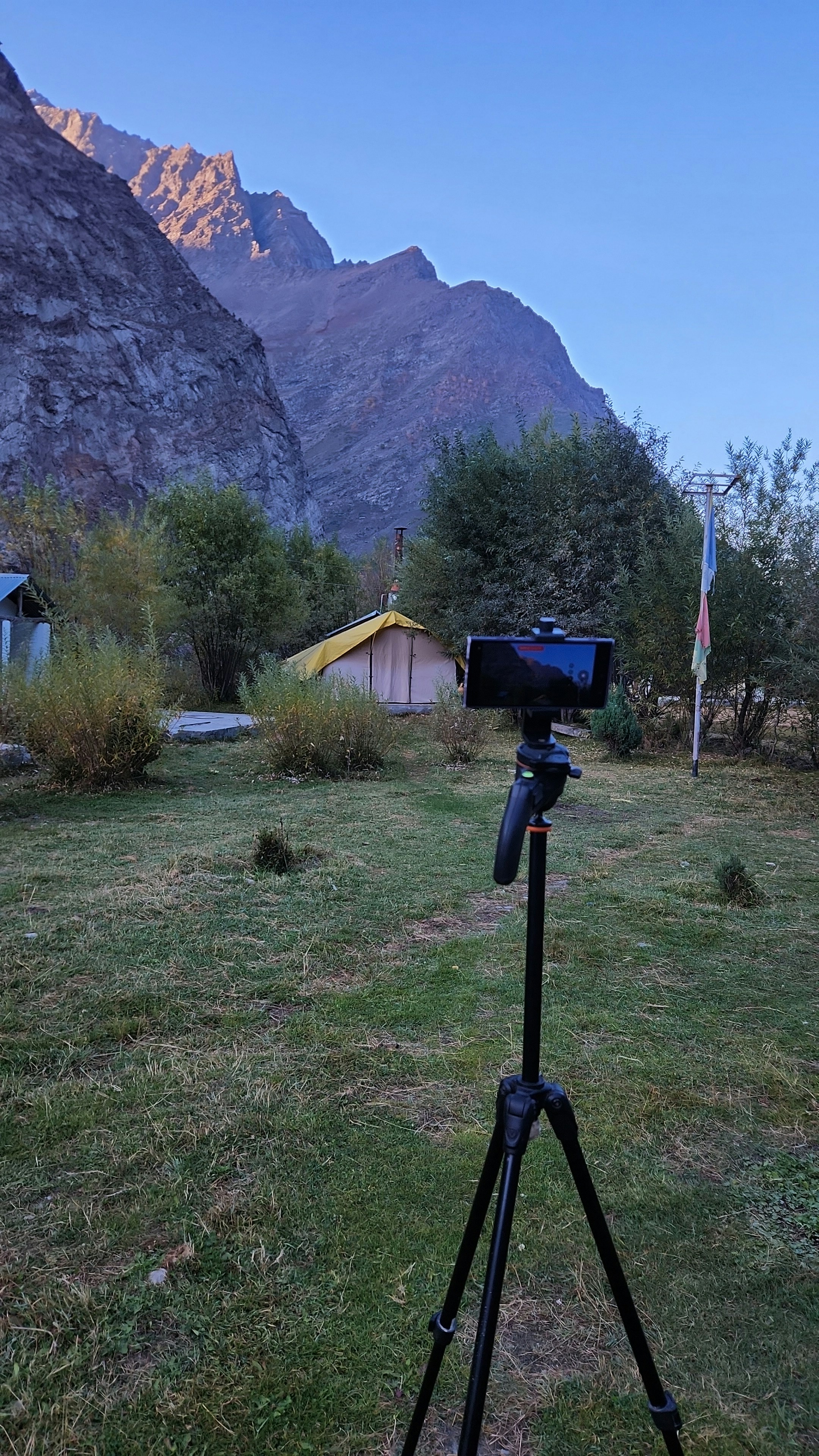 Smartphone on tripod capturing mountain landscape at dawn.