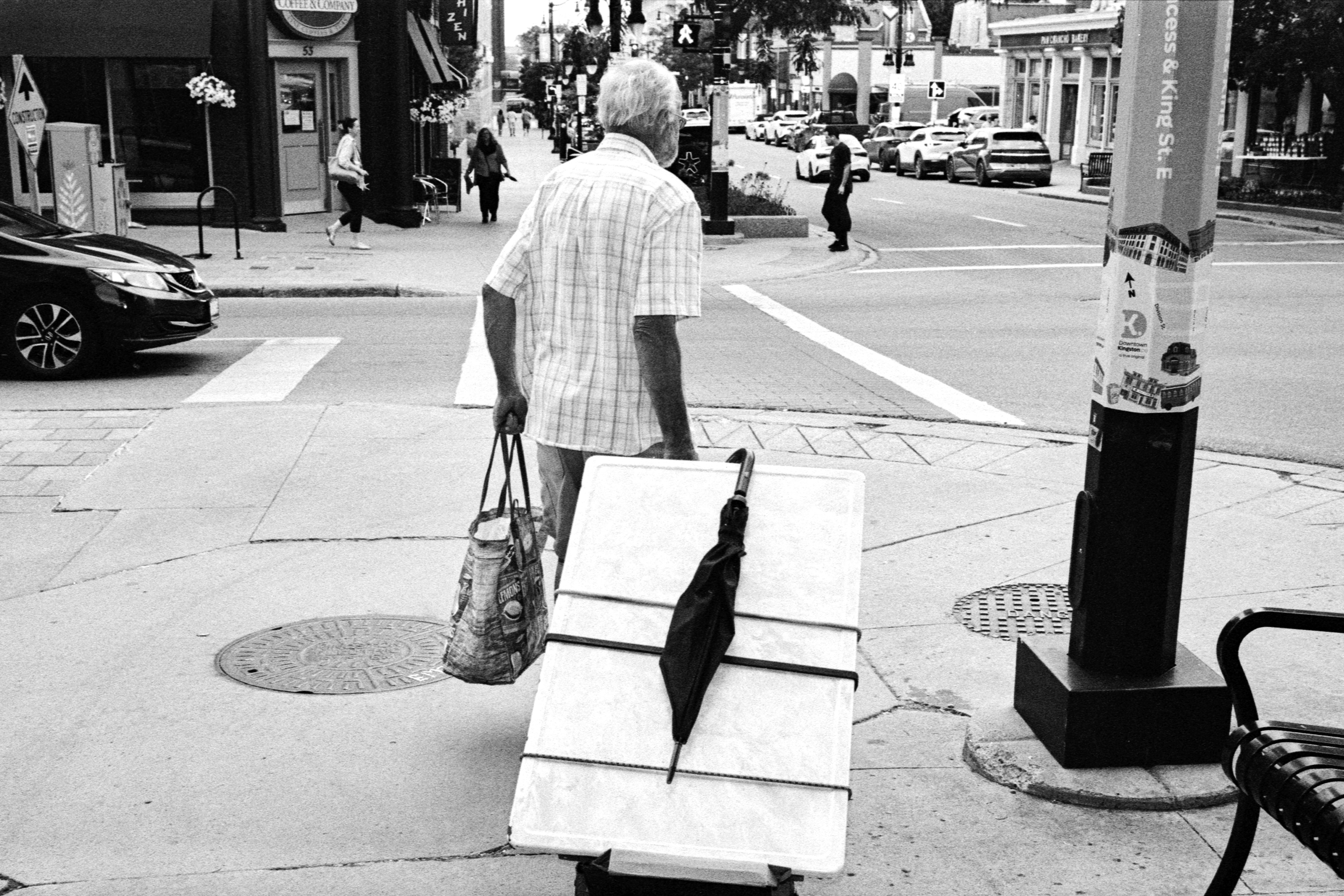 A man walks on a city sidewalk pulling a cart