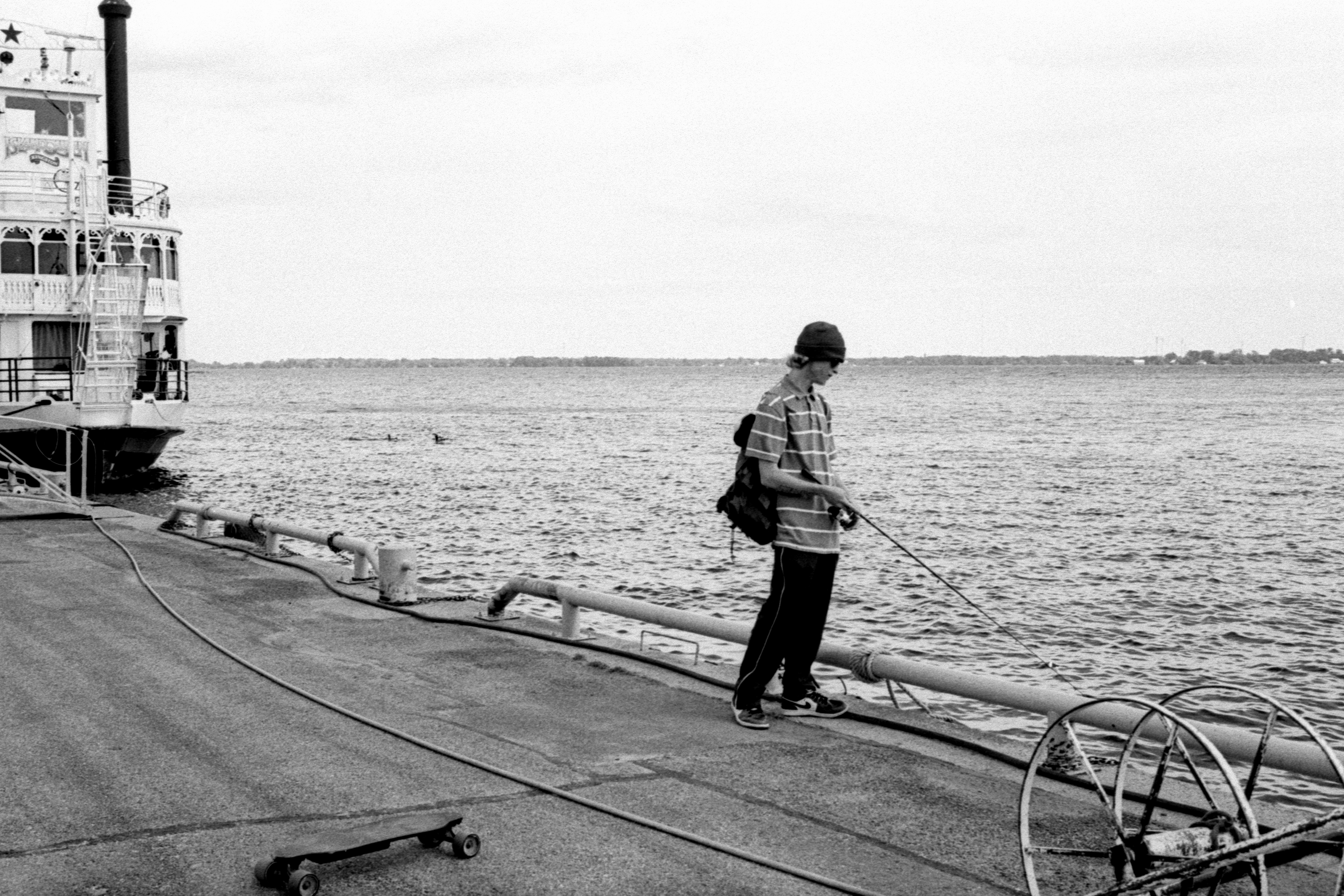 A person fishing from a dock with a large boat