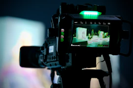Professional video camera captures an event, green light illuminated.