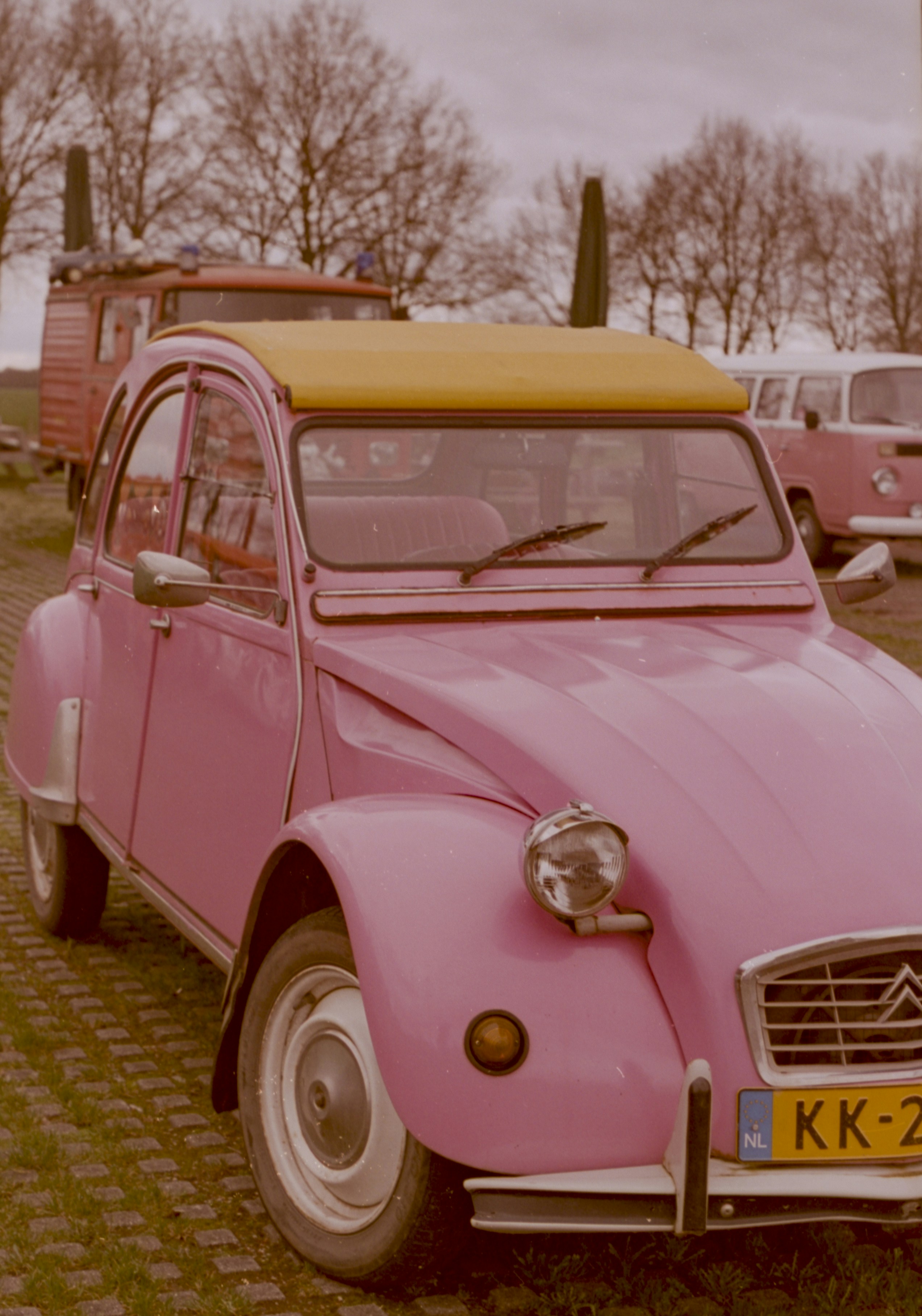 A pink citroën 2cv car with a yellow roof.