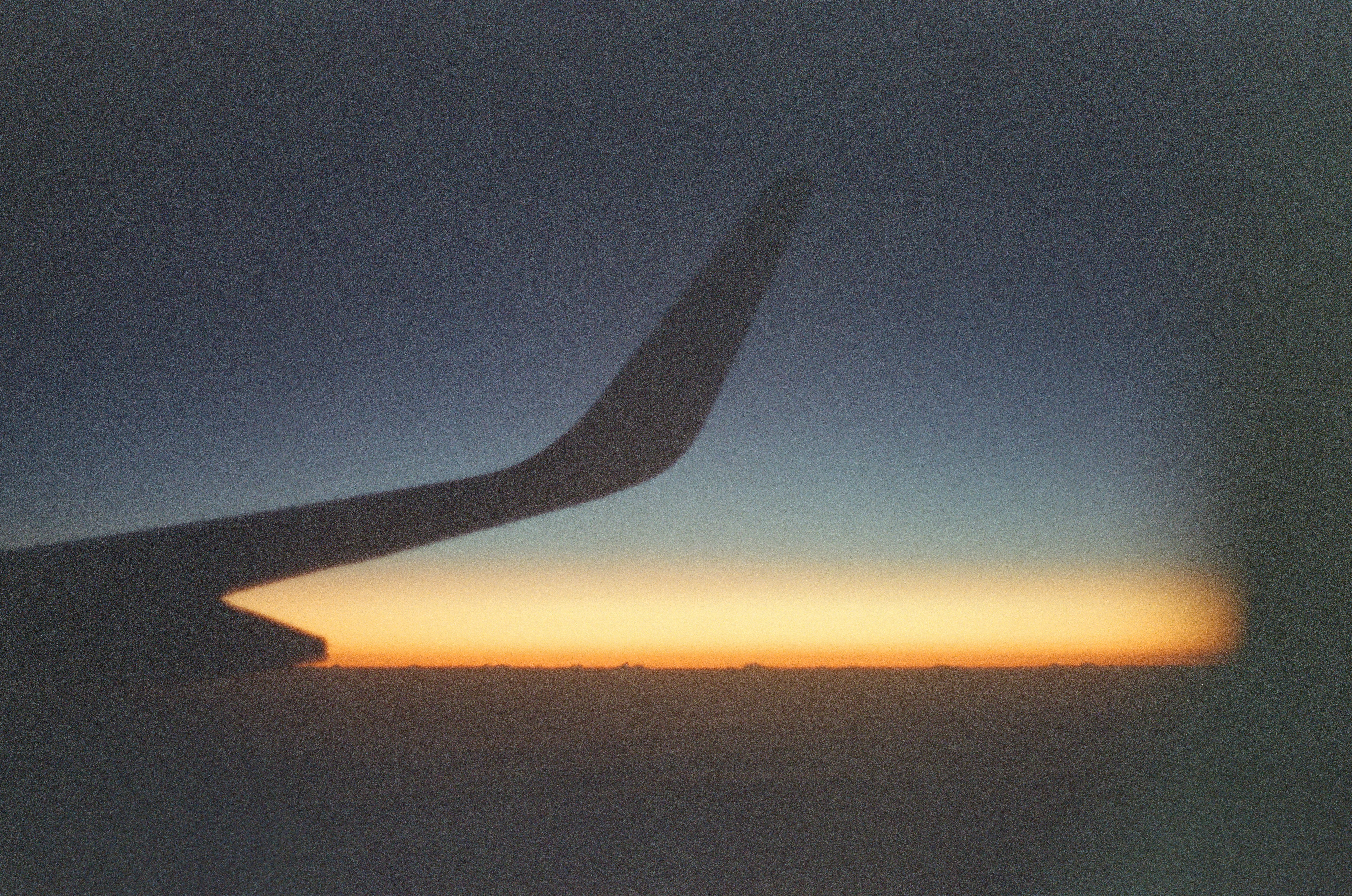 Airplane wing silhouetted against a colorful sunset sky.