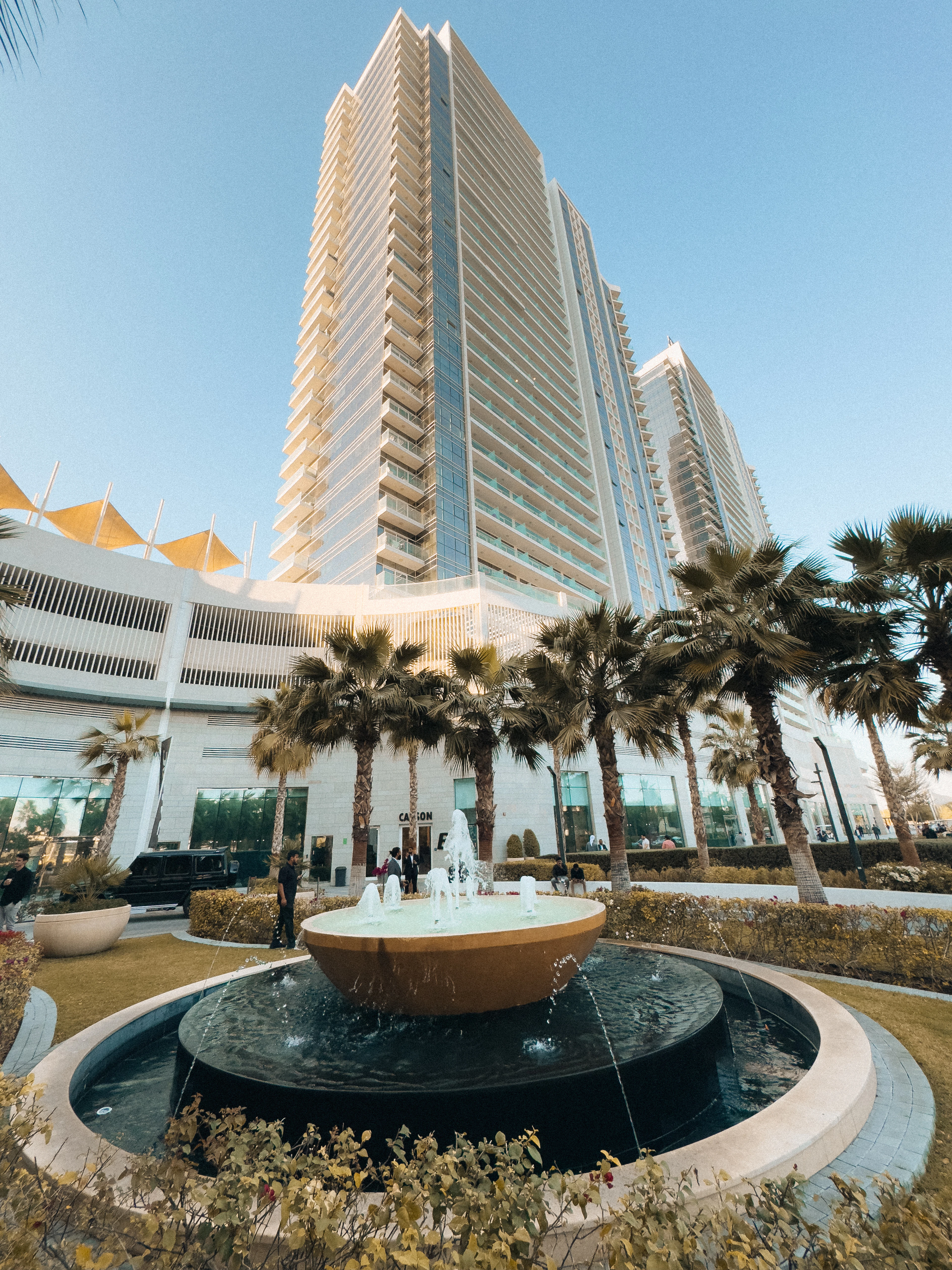 Modern apartment tower with a tiered fountain and palm trees