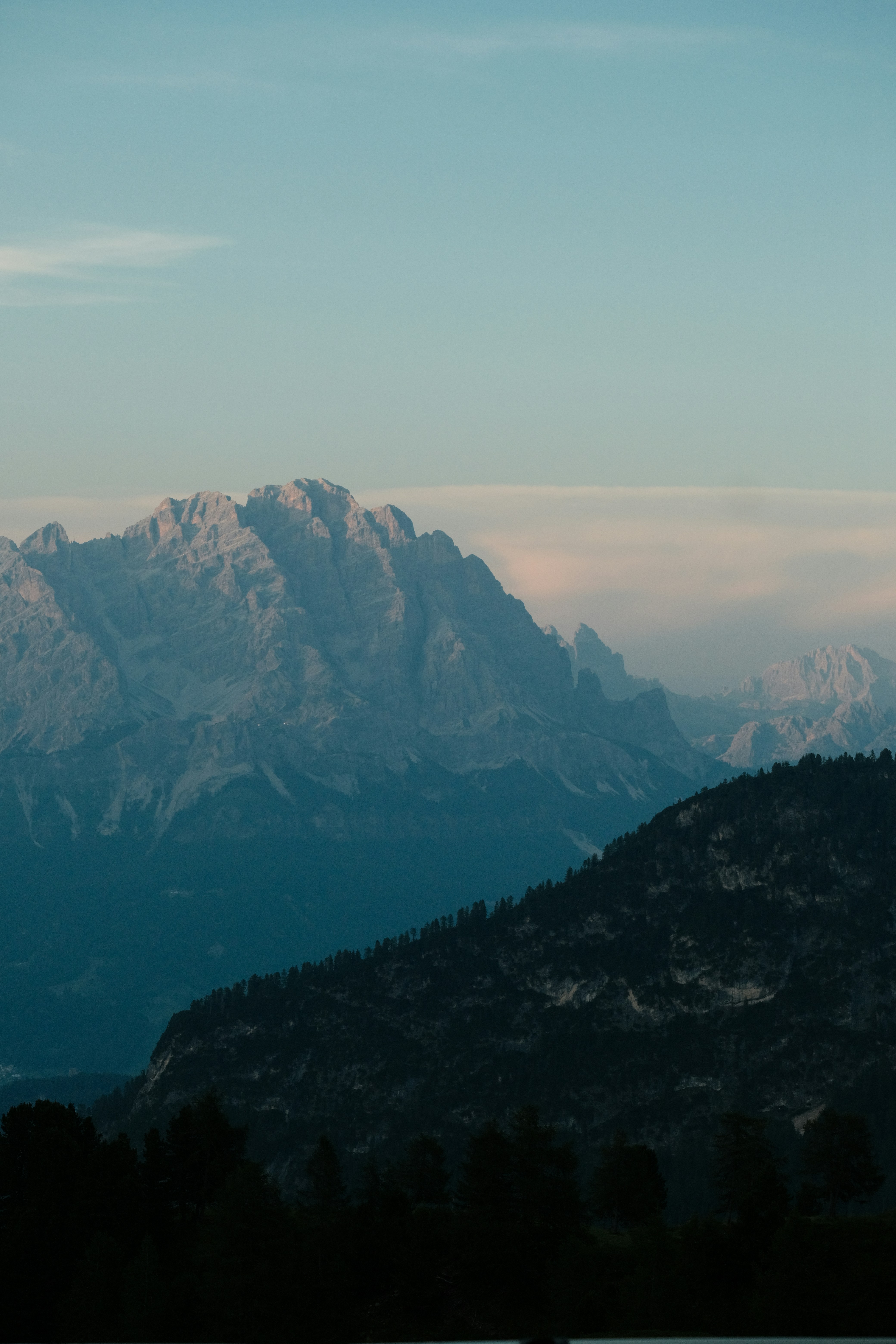 Layered mountain landscape with dark foreground and light peaks.