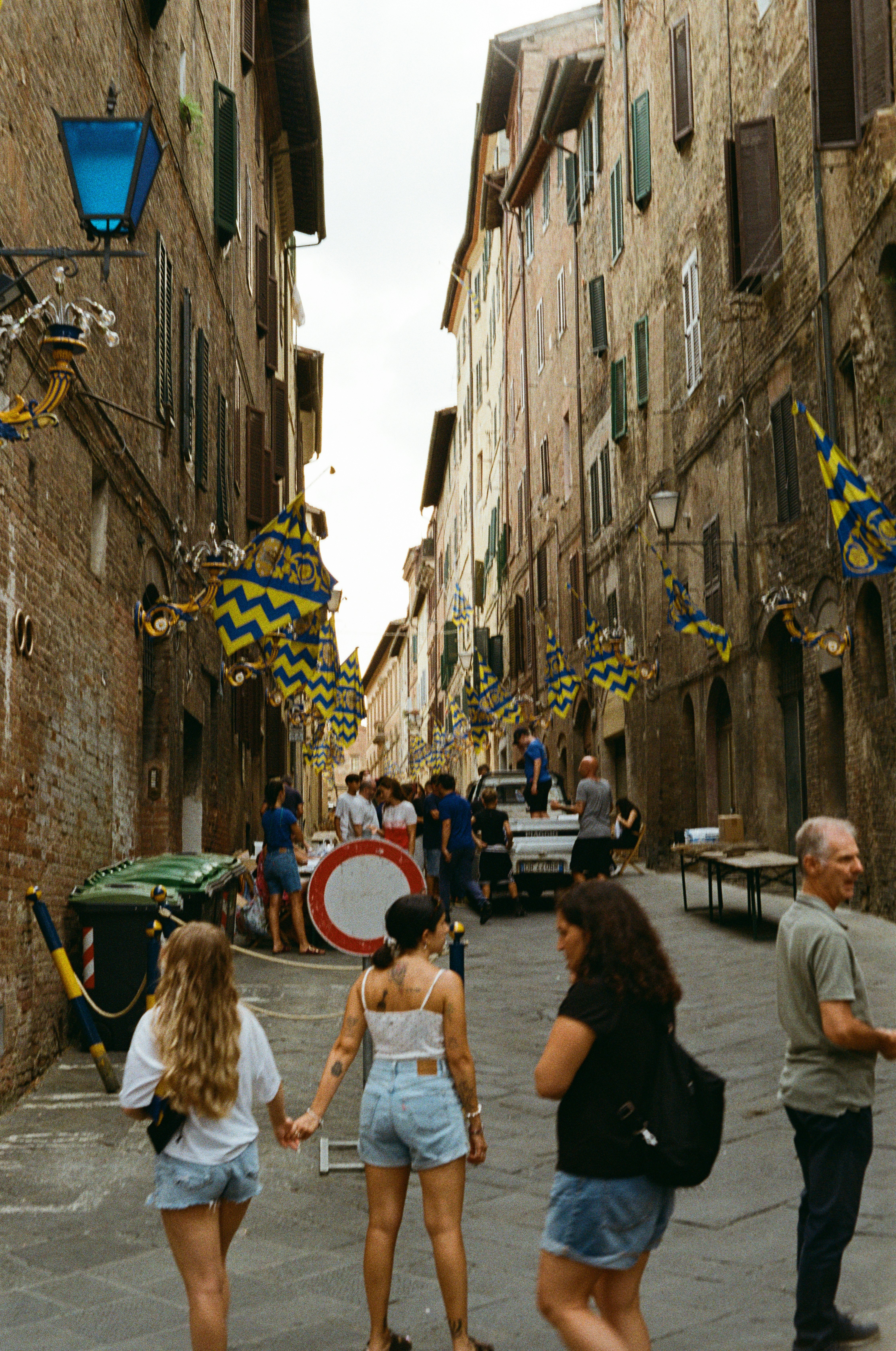 bandiere contrada blu e gialle sopra via Siena, gente intorno al tamburo