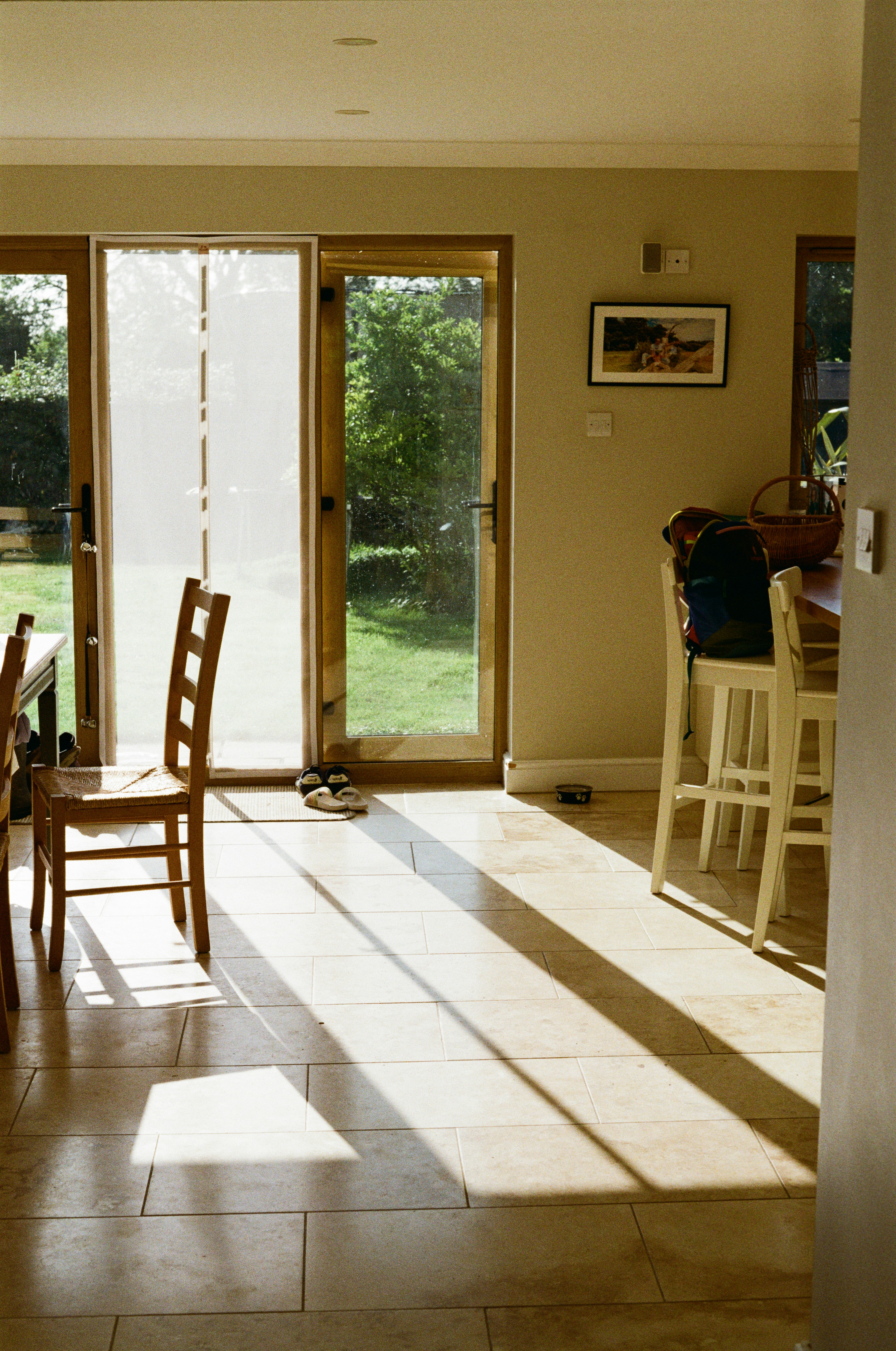 Morning sun on tiled kitchen-diner opening to green garden
