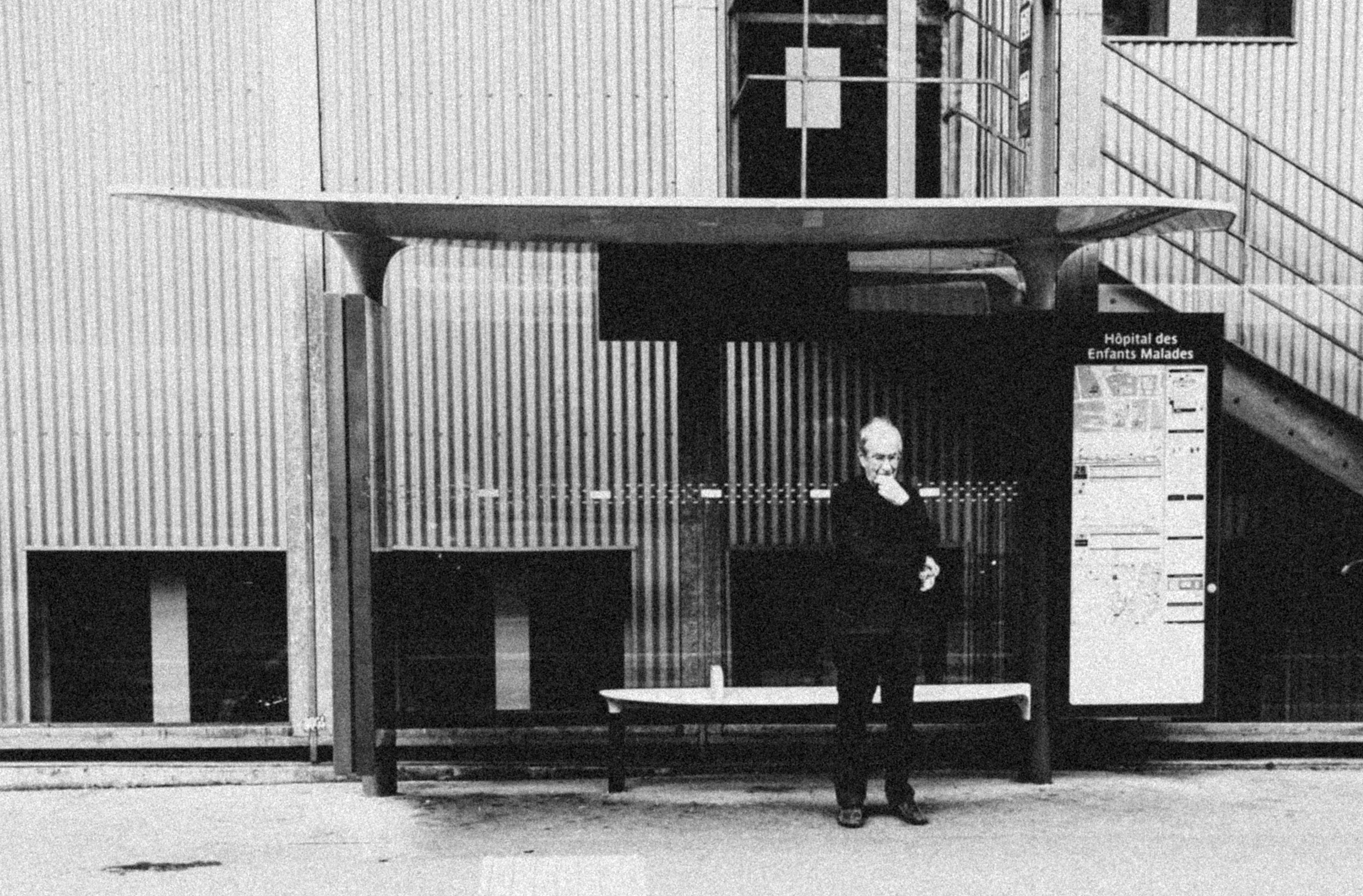 A man stands at a modern bus stop.