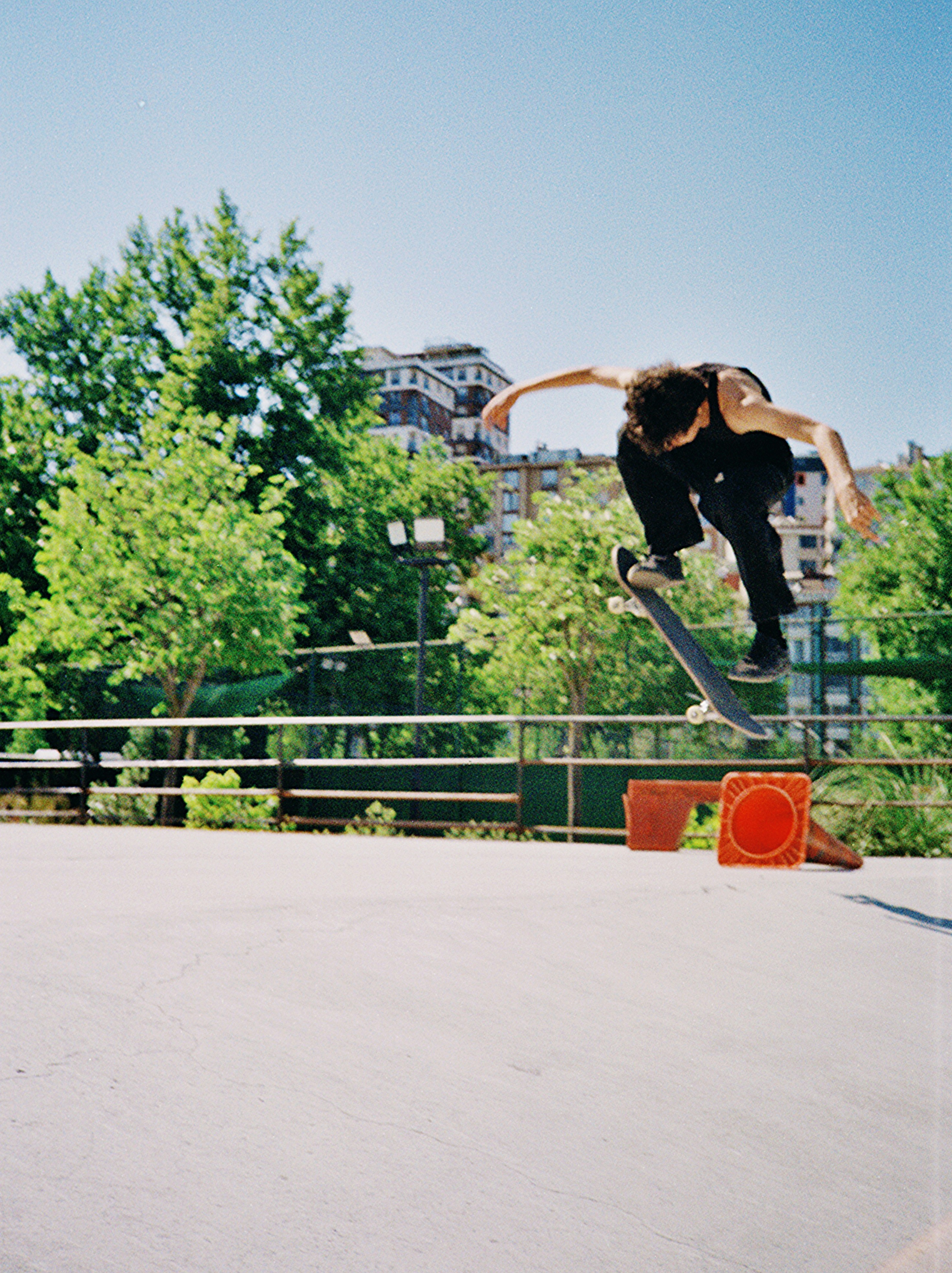 A skateboarder performs an aerial trick in an outdoor park.