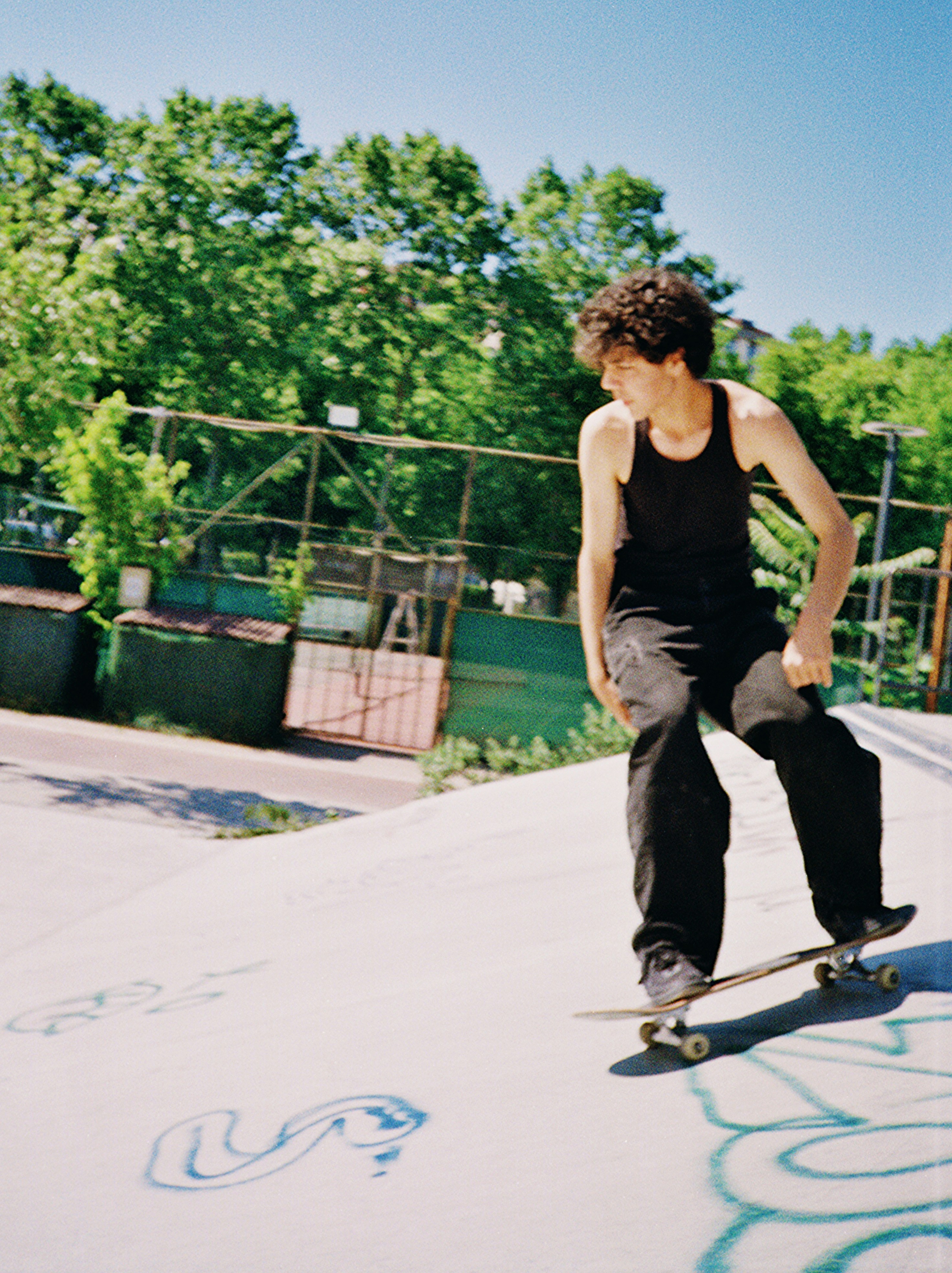 Teenager skateboarding on a concrete ramp with graffiti.