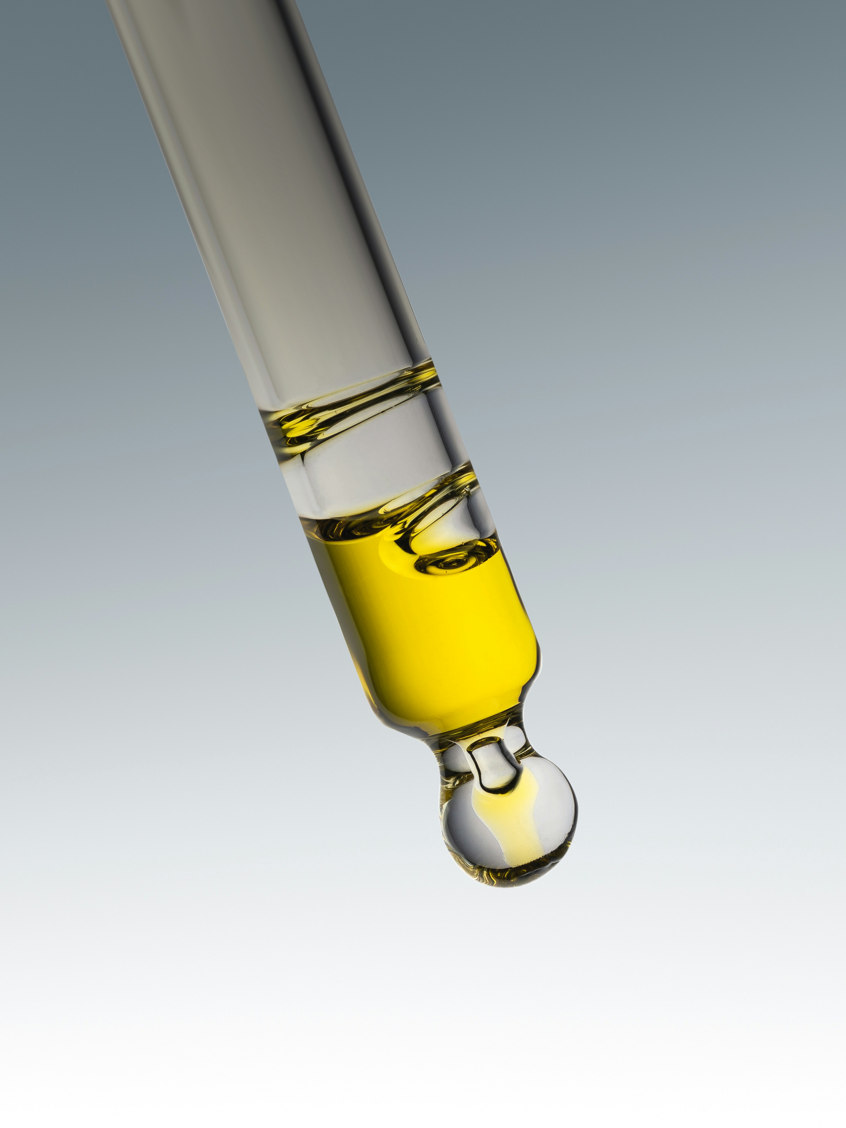 Yellow liquid dripping from a glass pipette