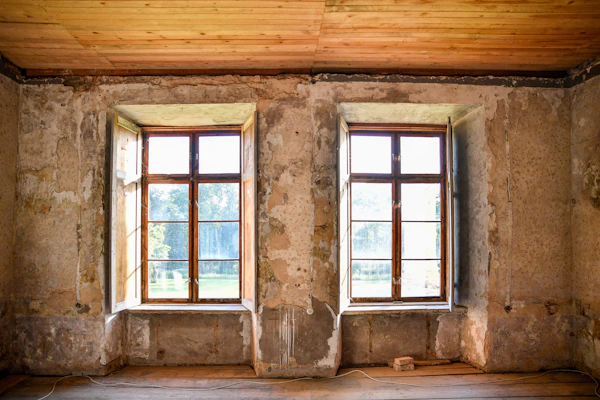 Tomt rom i gammelt hus med to vinduer og slitte vegger