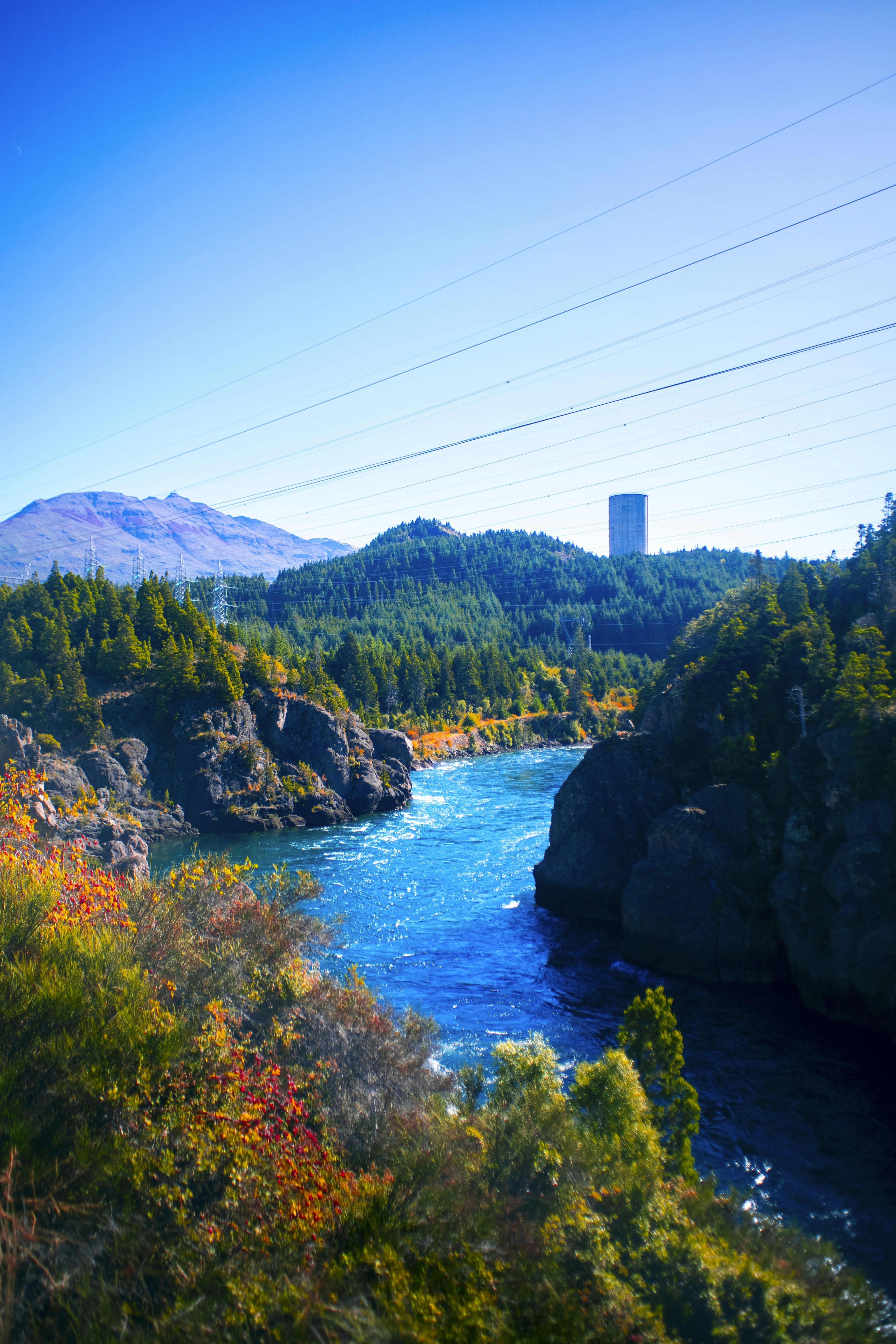 Bright blue river flows through a rocky, forested gorge.