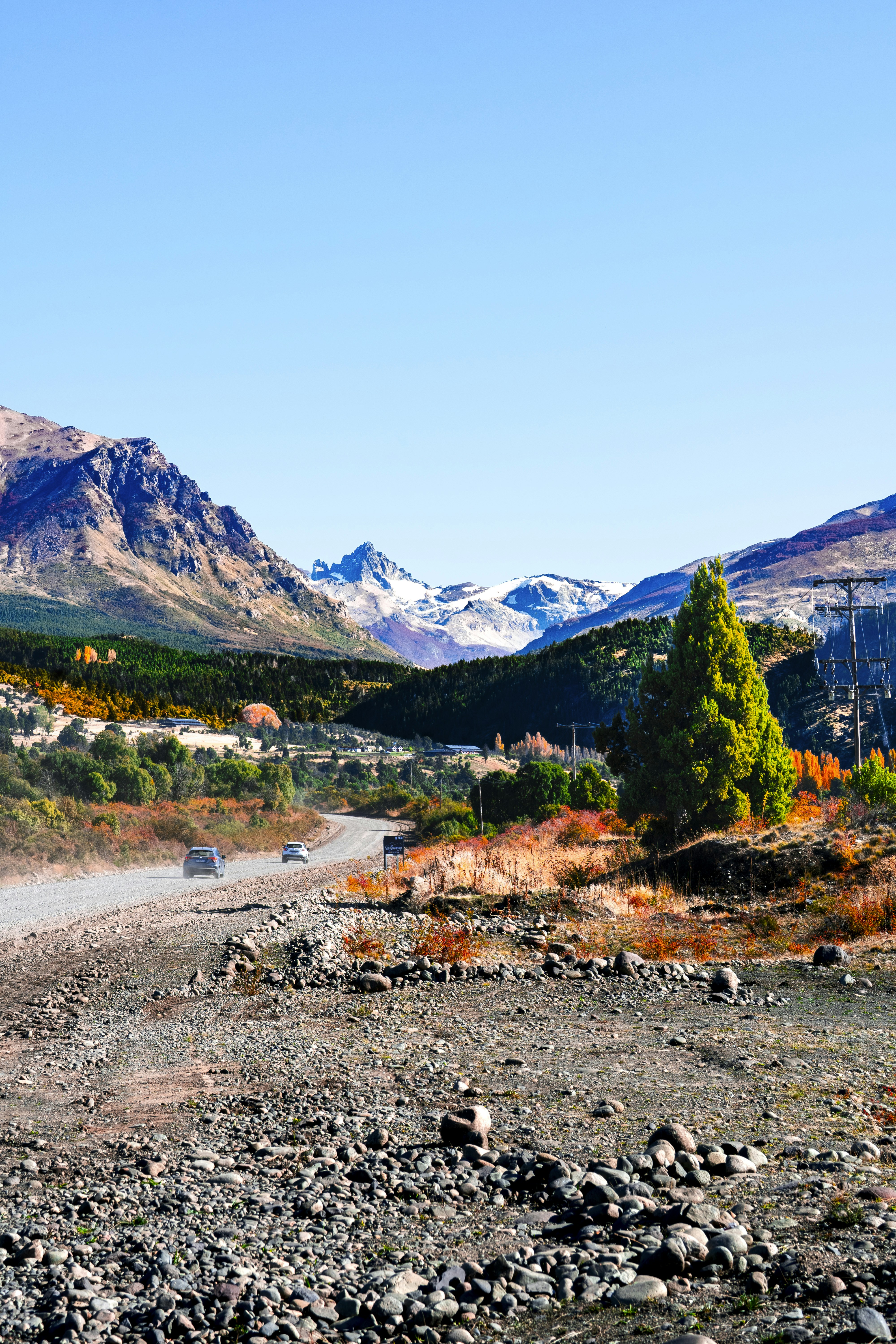 A winding road through a mountainous landscape with autumn trees.