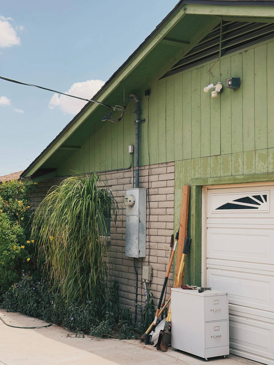 A green house with a meter and service on the side wall