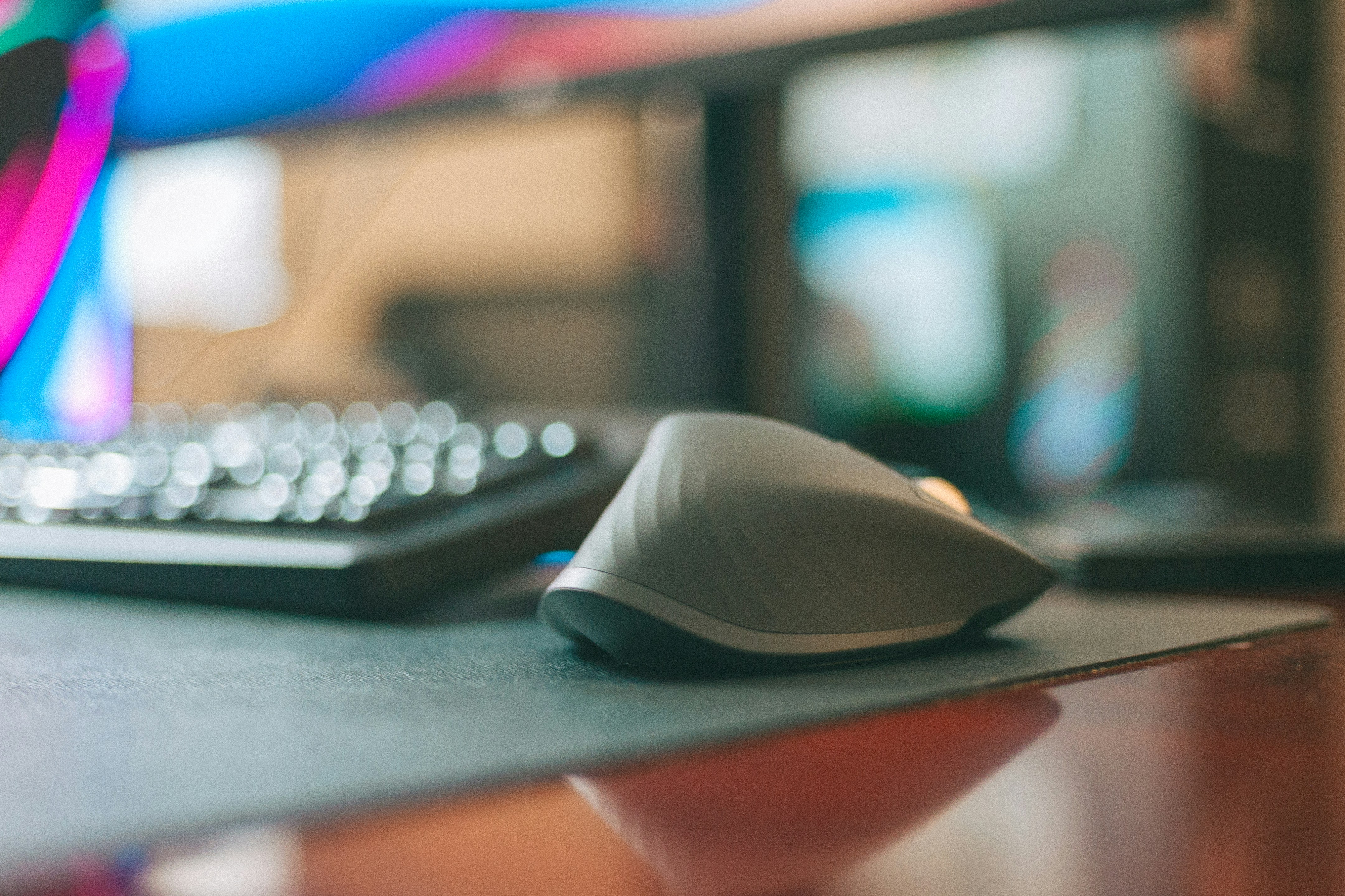Ergonomic computer mouse on a mousepad next to a keyboard.