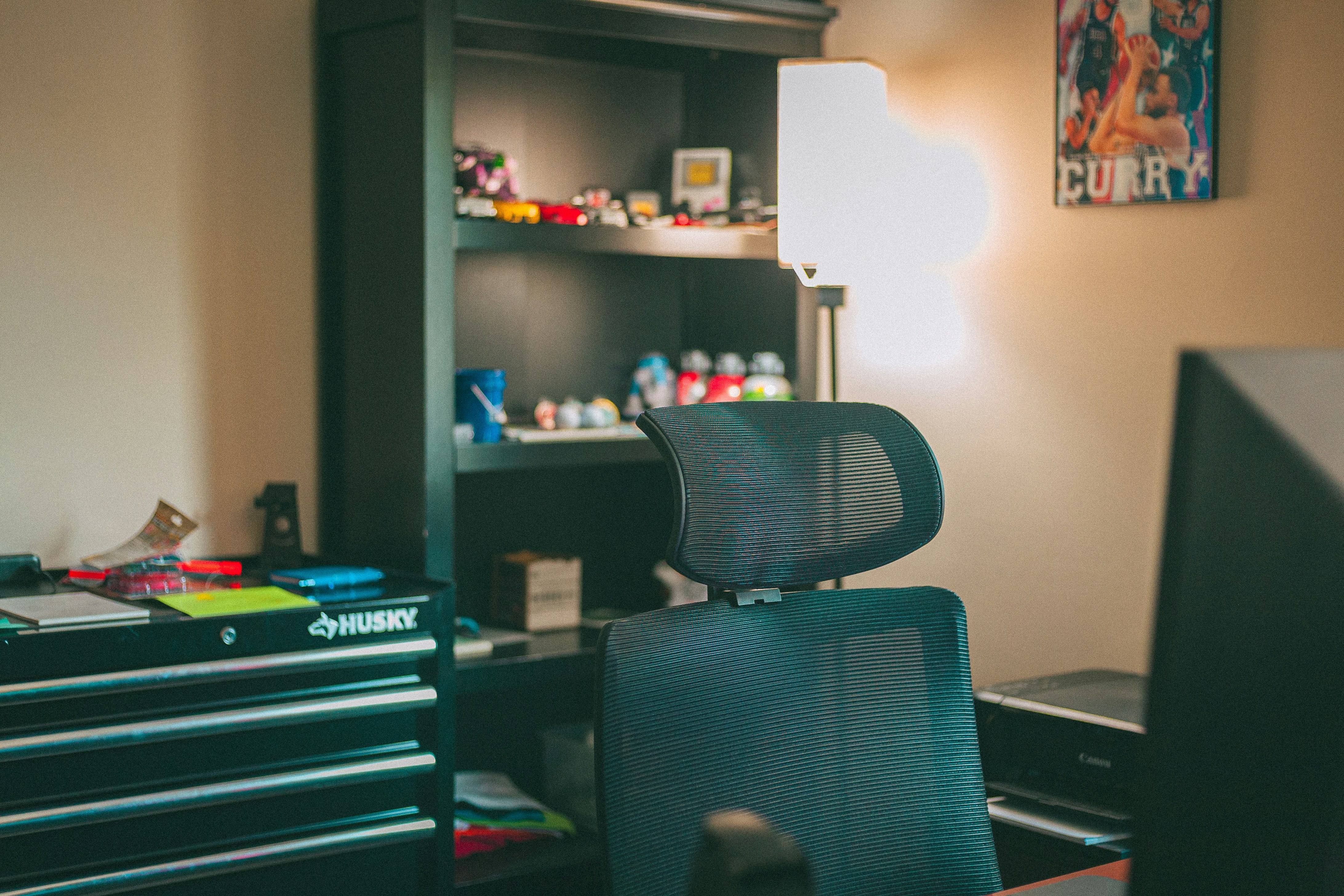 Organized home office with black furniture and bright lamp.