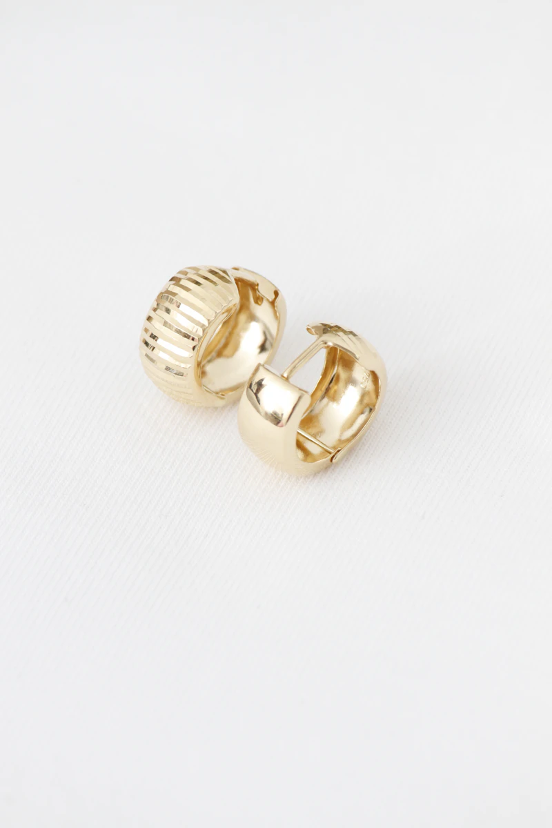 Chunky polished gold huggie hoop earrings on a white background