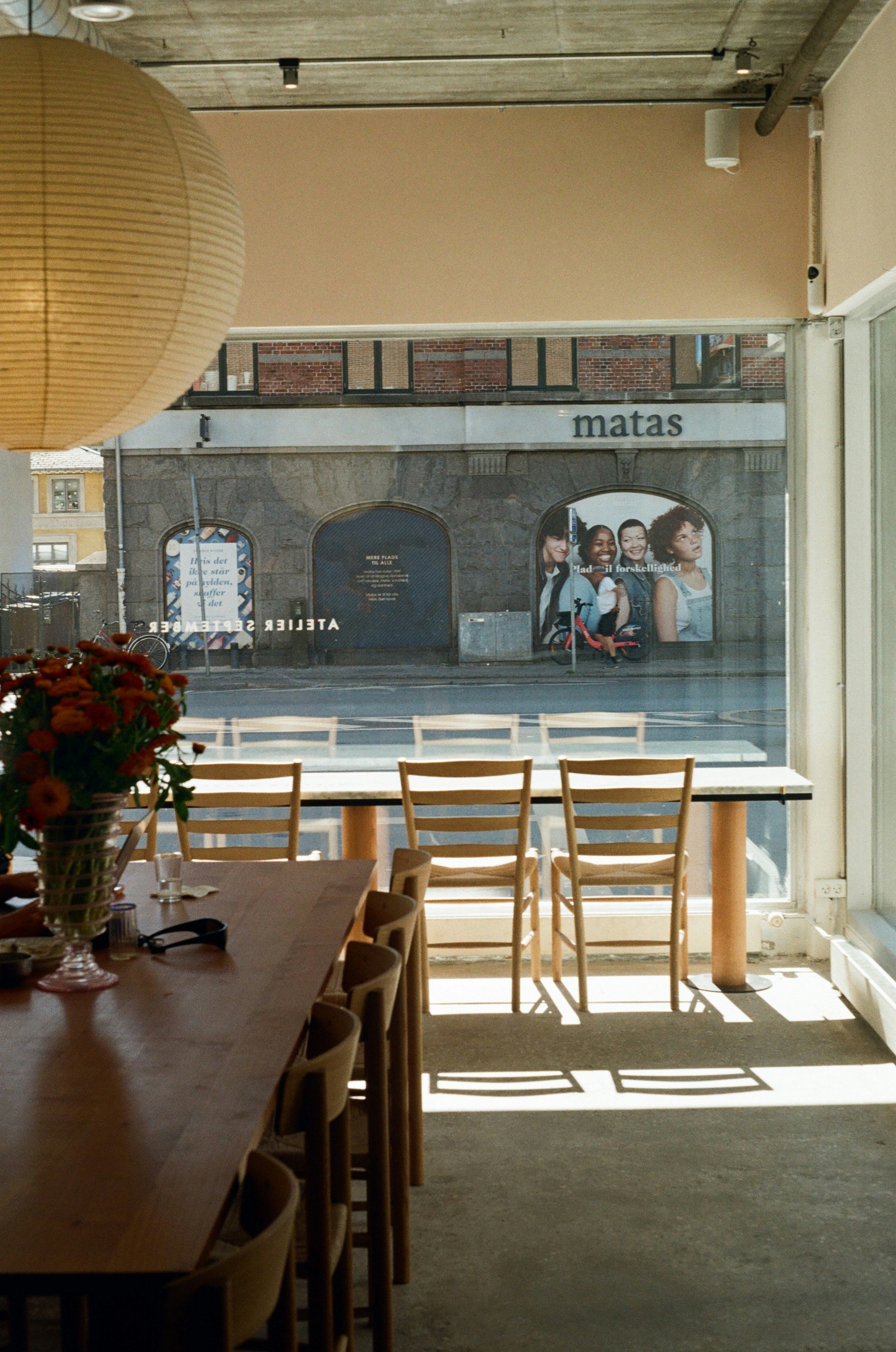 Sunny cafe interior with wooden furniture and a street outside.