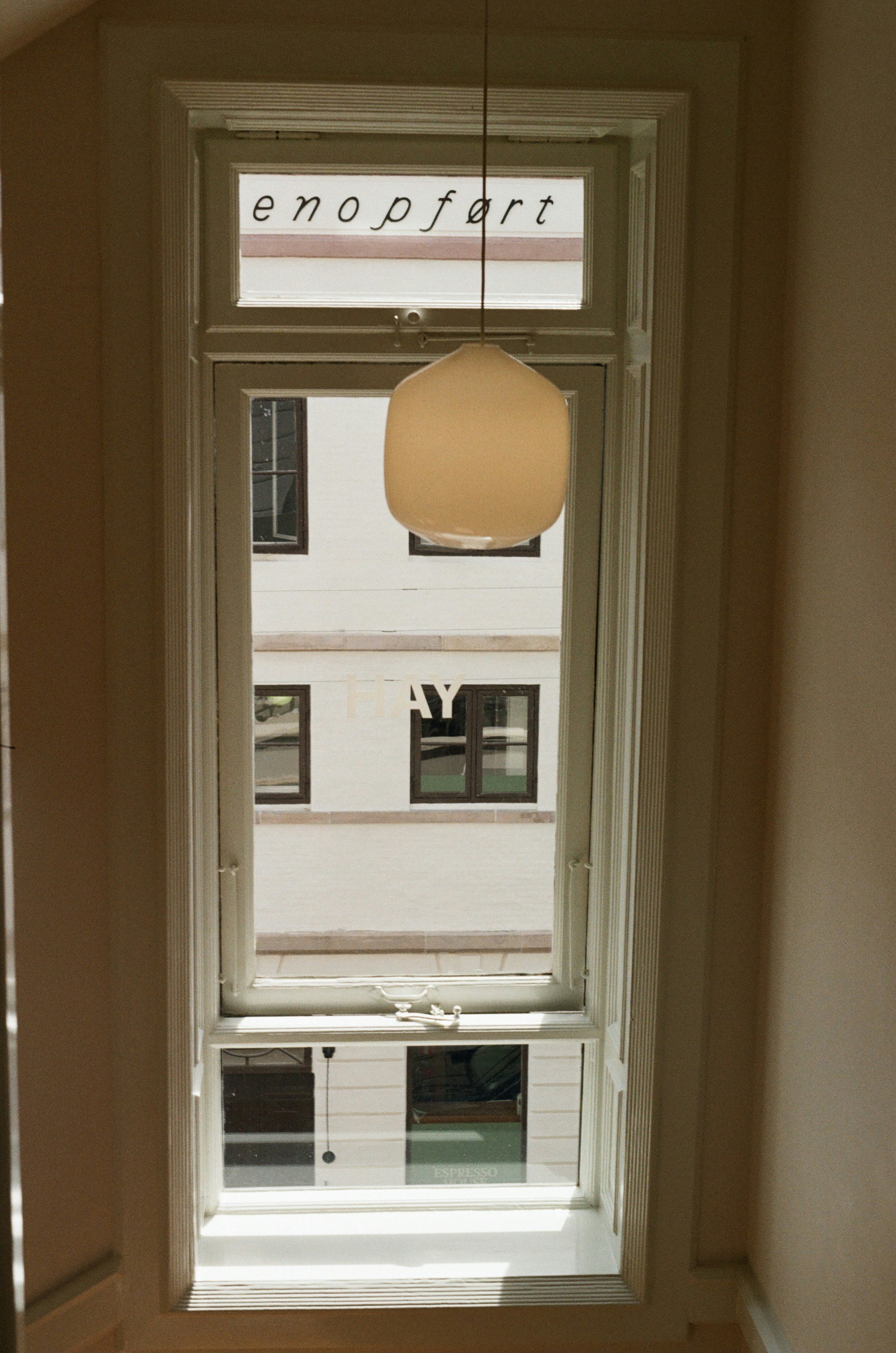 Tall window, hanging light, and view of a white building.