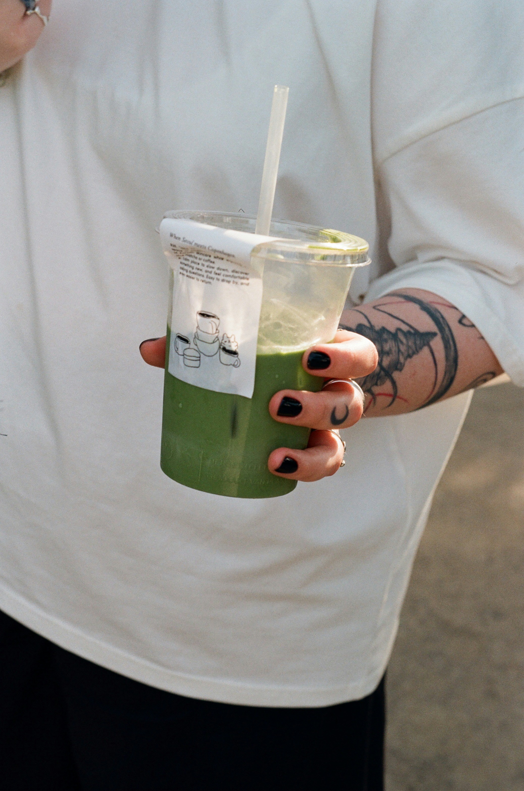 A person holding an iced green matcha drink.