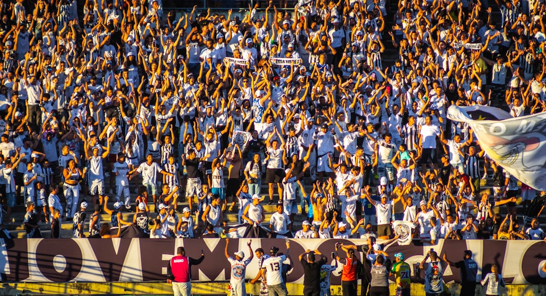 Large crowd of fans cheering with raised hands.