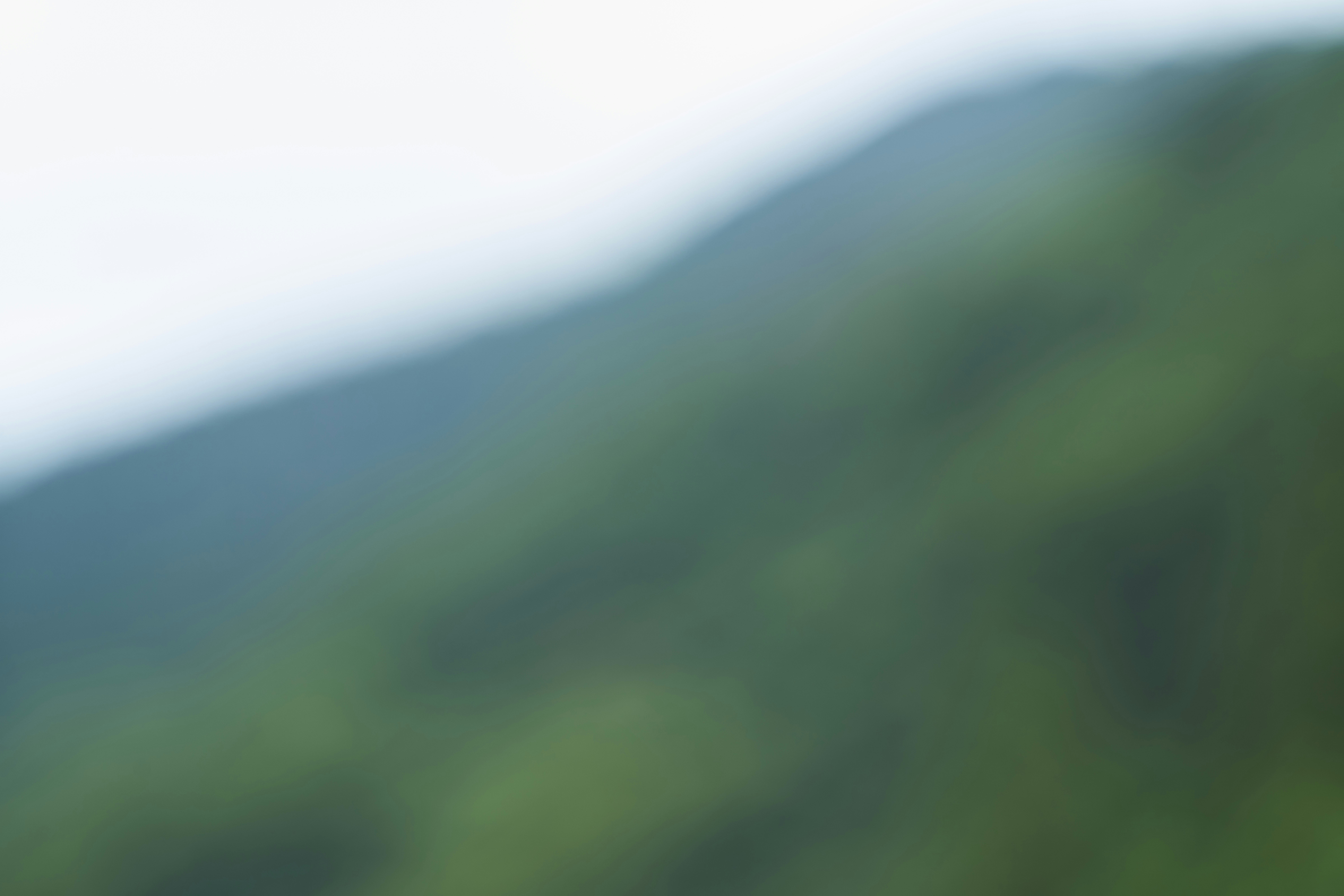 Blurred green mountain slope under a light sky