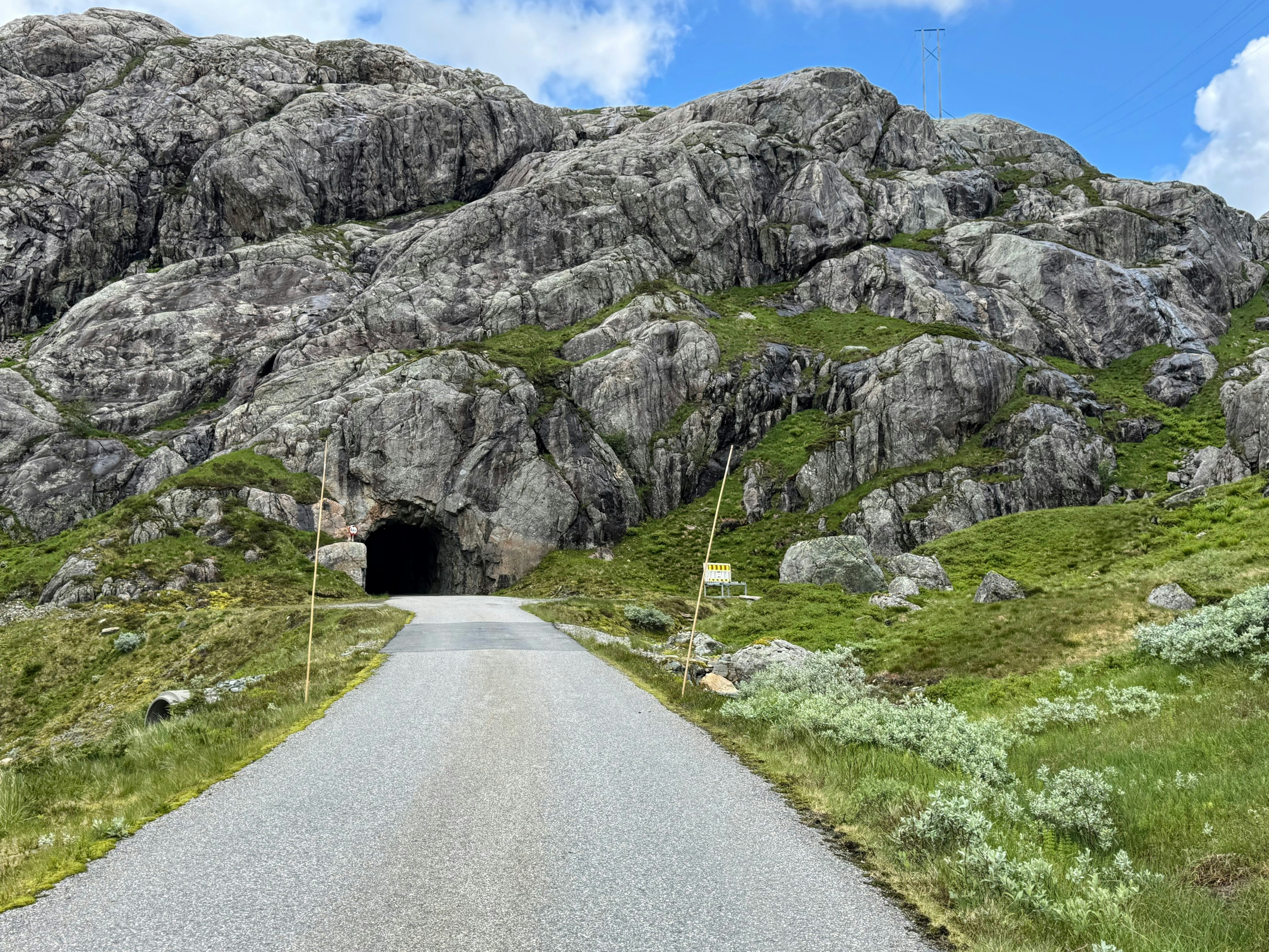 A road enters a dark tunnel in a rocky mountain.