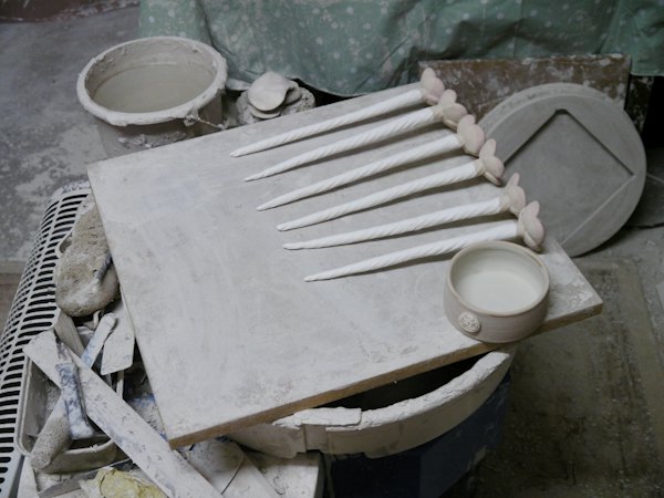 Un plan de travail de potier, avec des outils et une plaque d’argile