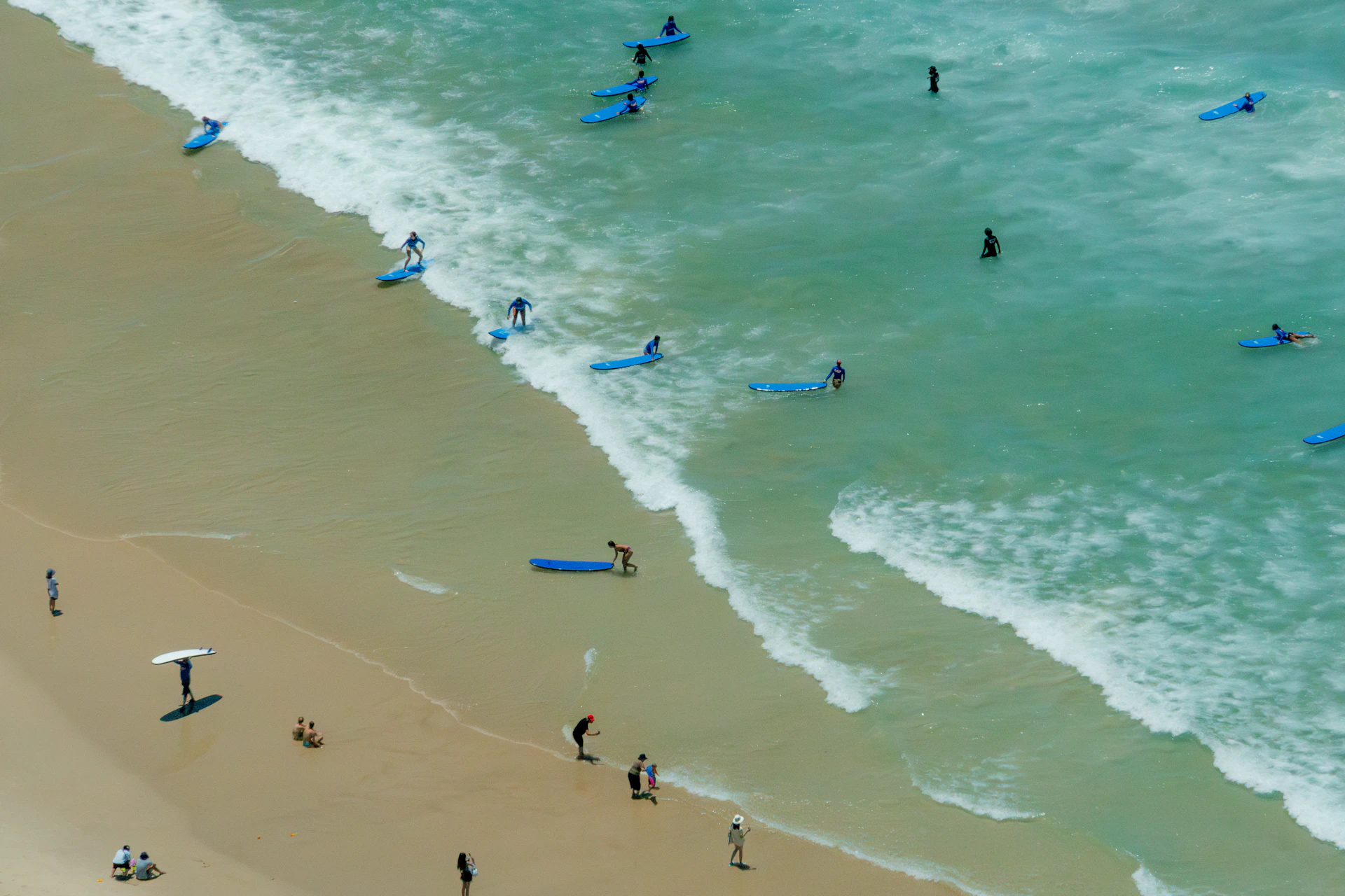 Surfers and beachgoers enjoying the sunny ocean waves