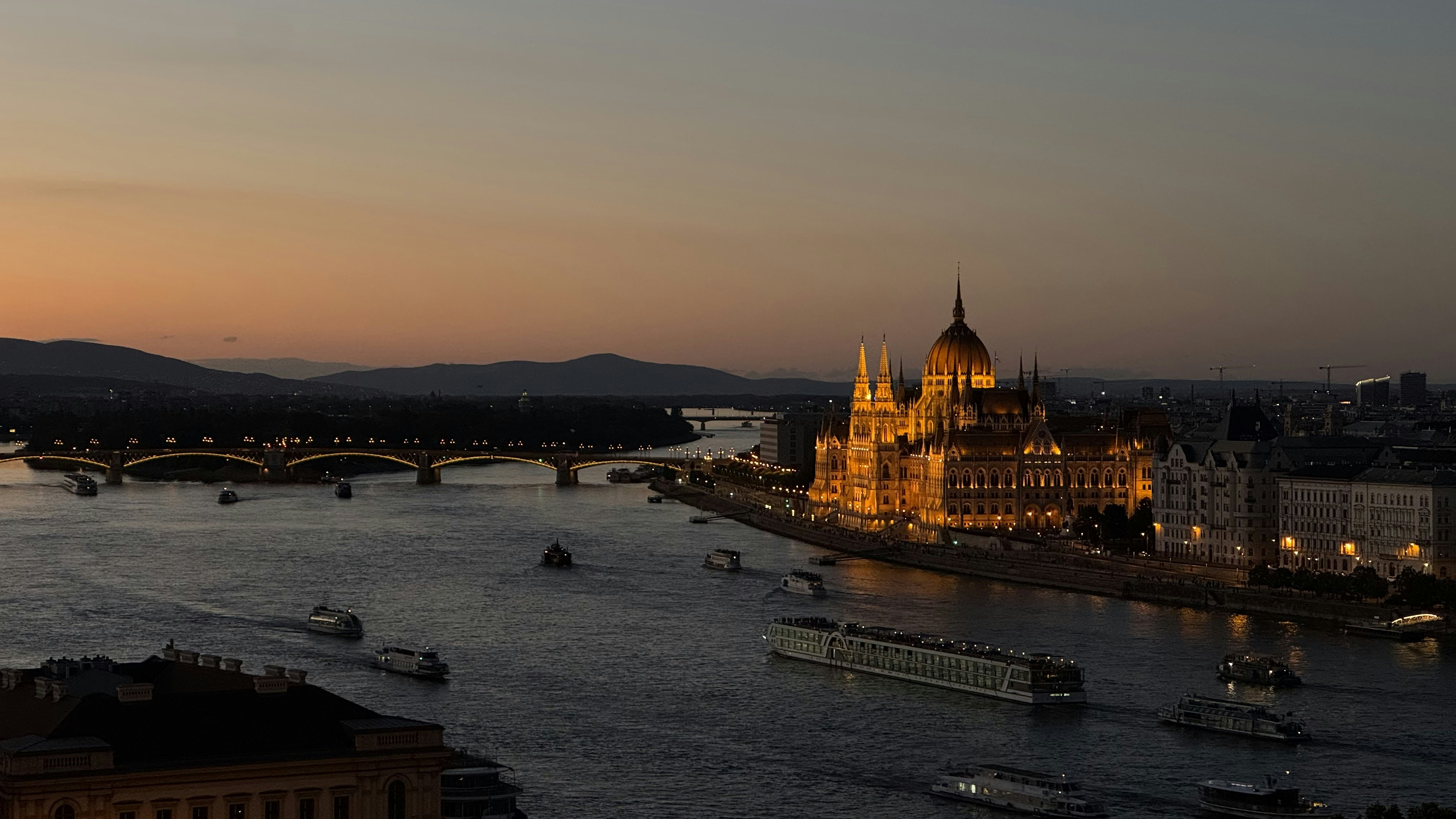 Budapest parliament building illuminated beside the danube river at dusk