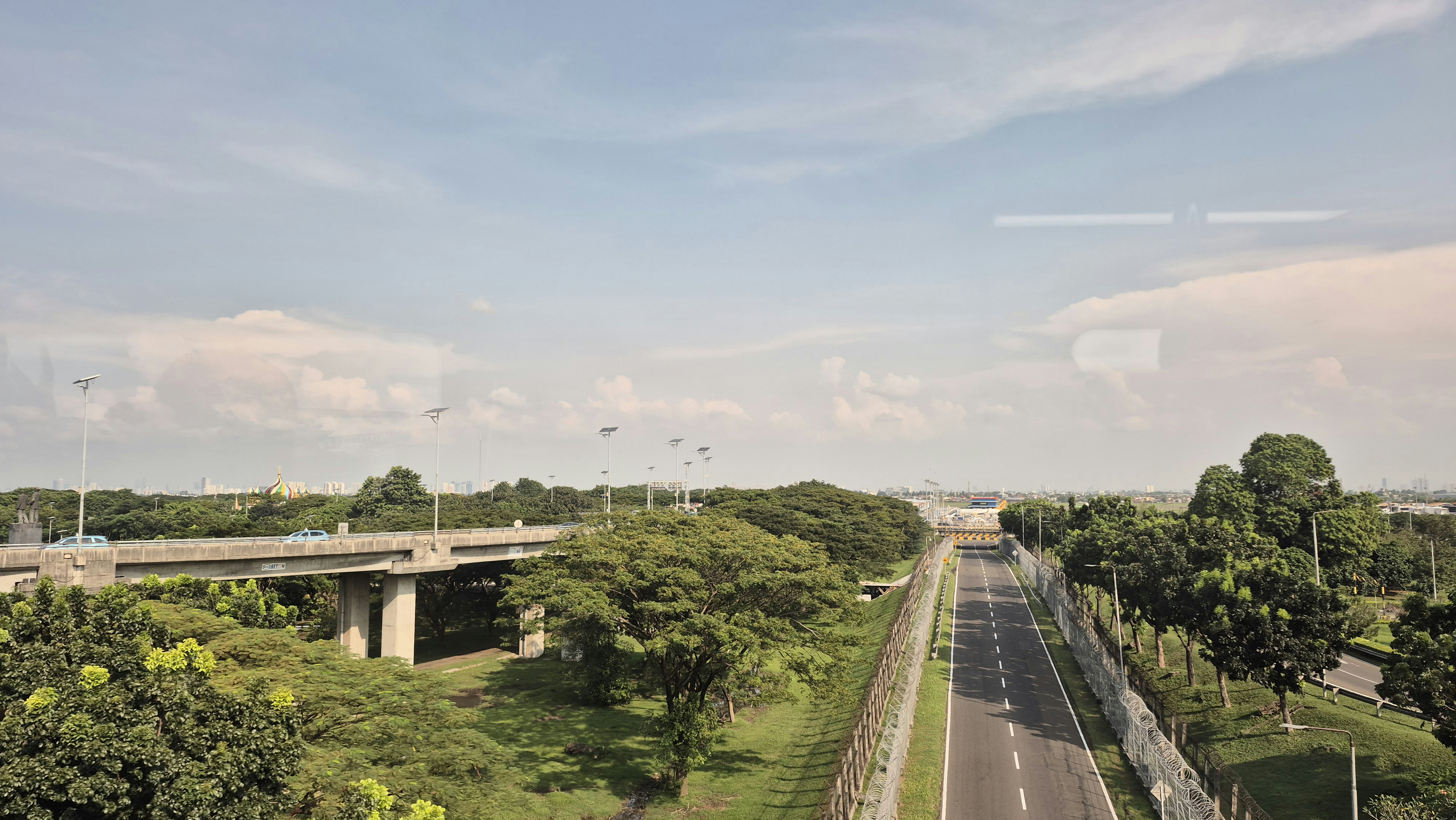 Uma estrada longa com uma ponte elevada e árvores verdes.