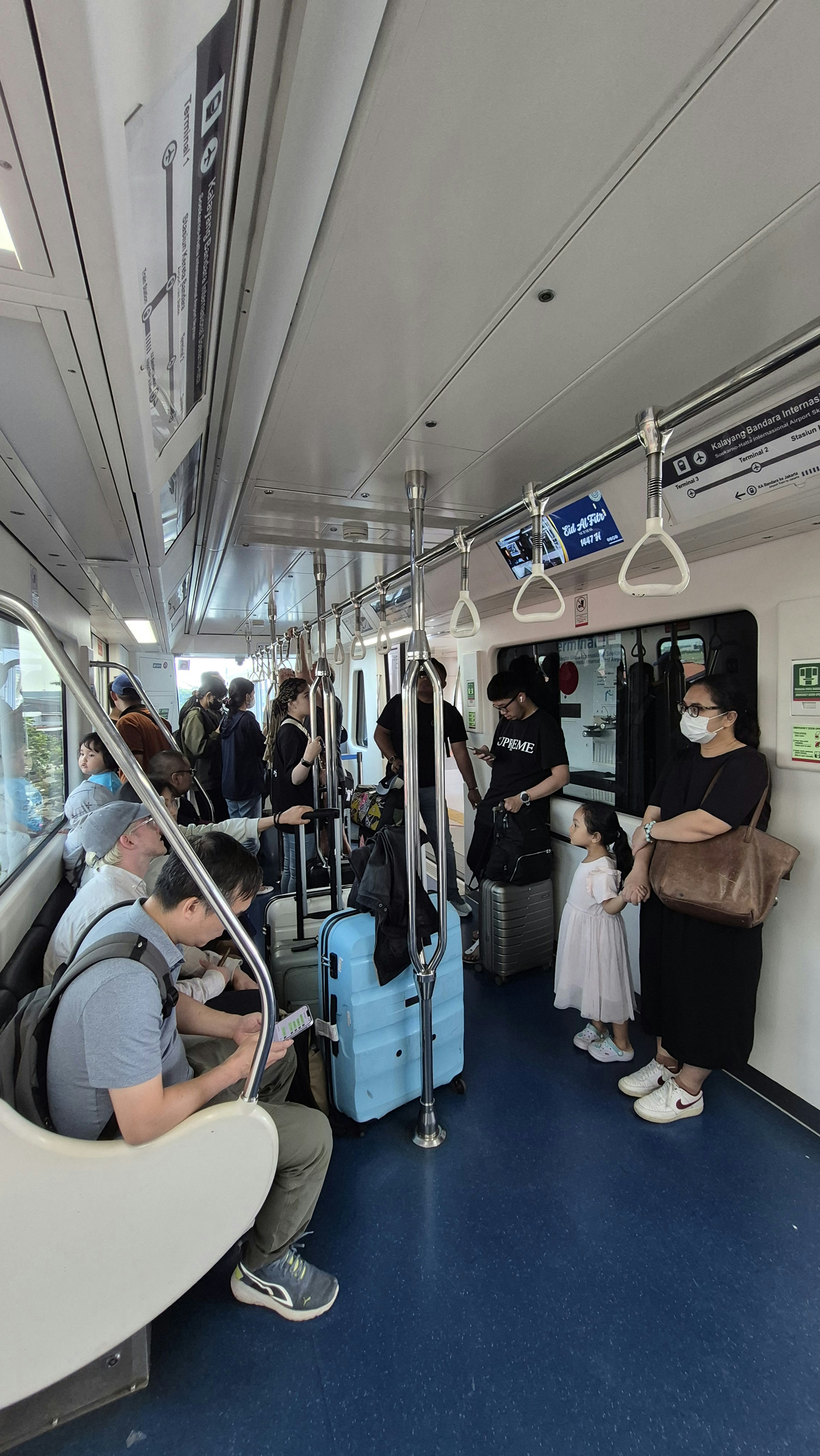 Interior de trem lotado, com passageiros diversos e suas bagagens.