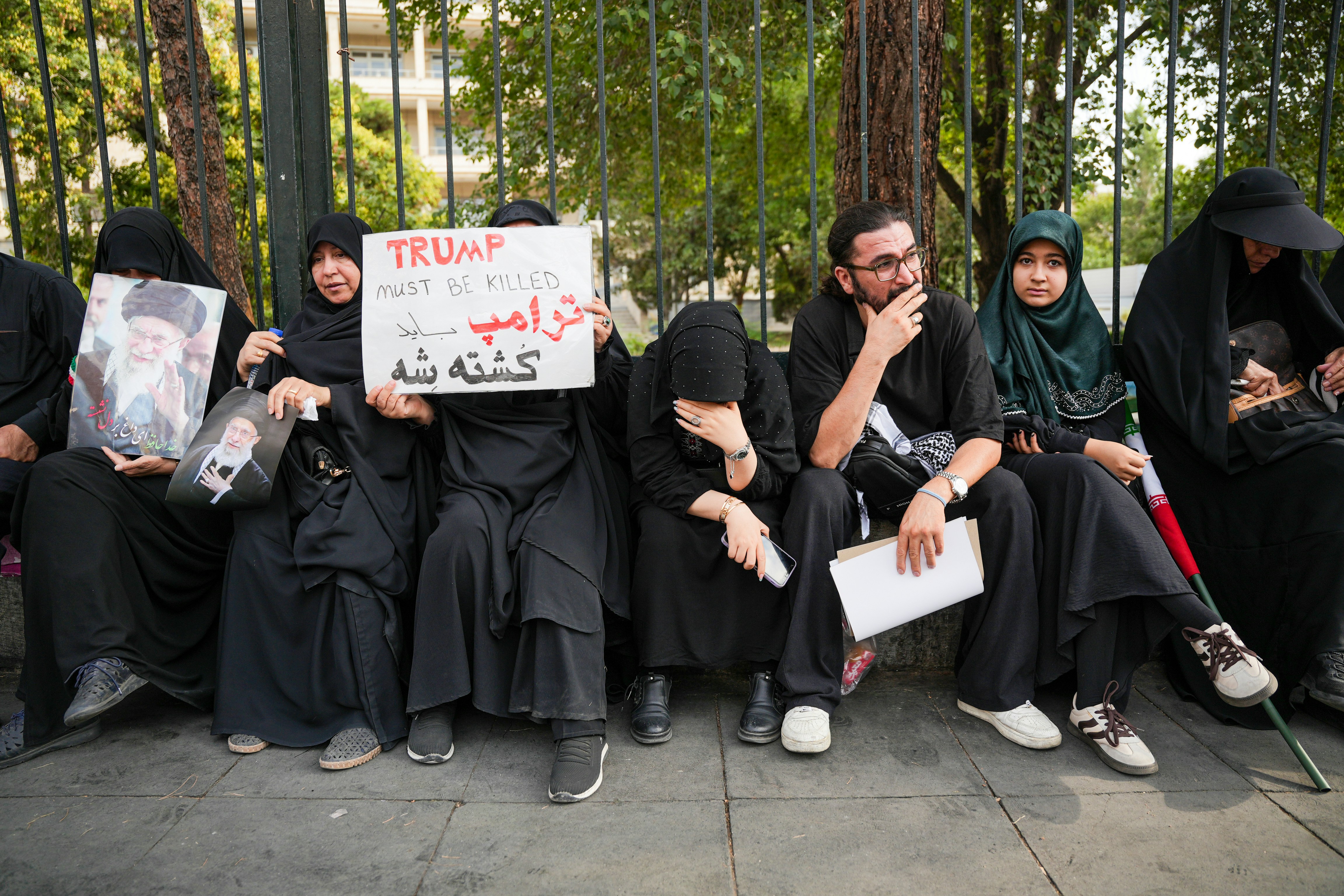 Protesters in black attire holding signs and portraits.